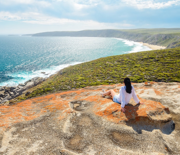Woman enjoying the scenery while sitting on the edge of the cliff at Remarkable Rocks, Kangaroo Island, South Australia License Type: media Download Time: 2023-08-21T07:29:02.000Z User: lonelyplanetmedia Is Editorial: No purchase_order: