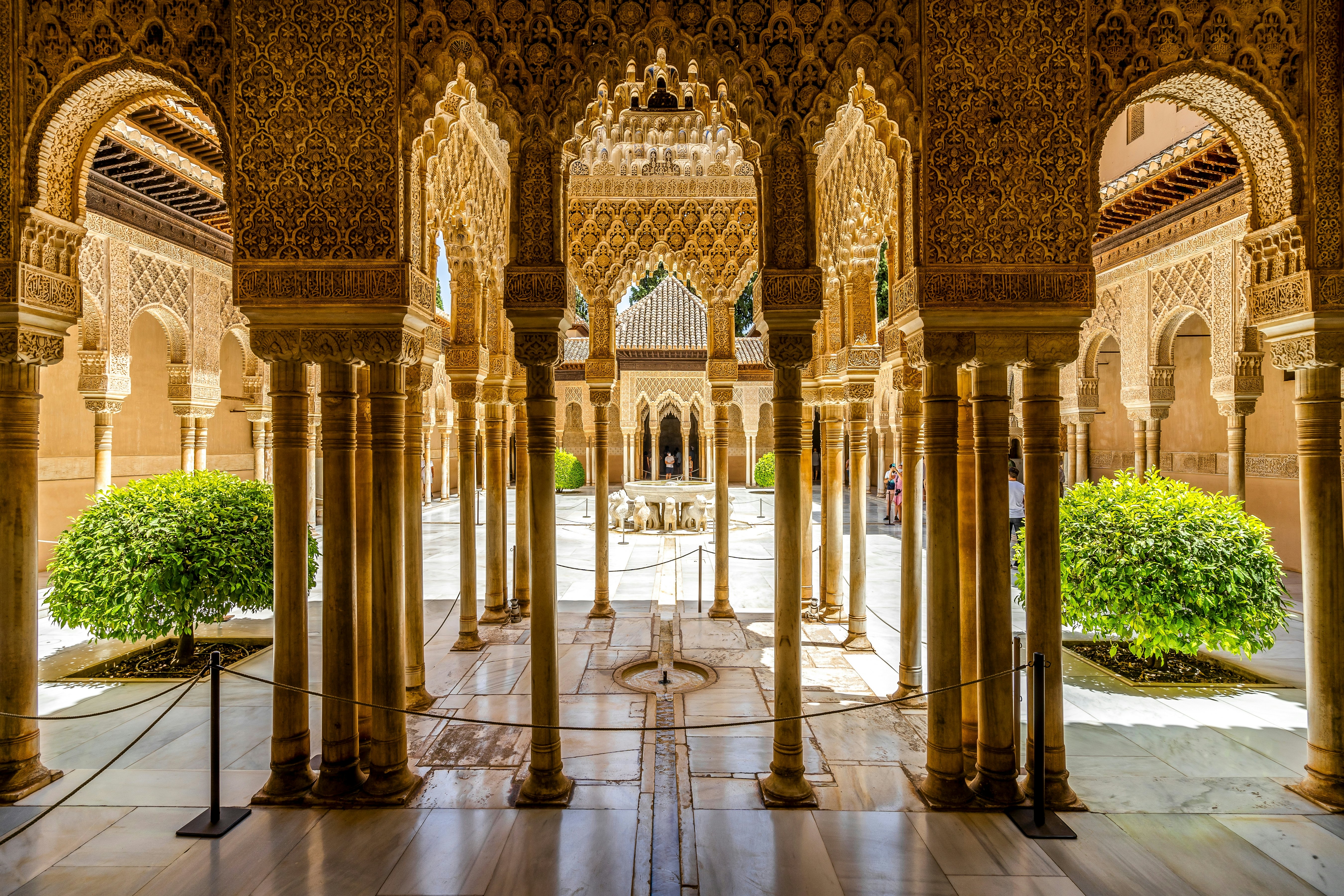 A courtyard with many columns, carved archways and a fountain in the center with sculptures of lions around the base.
