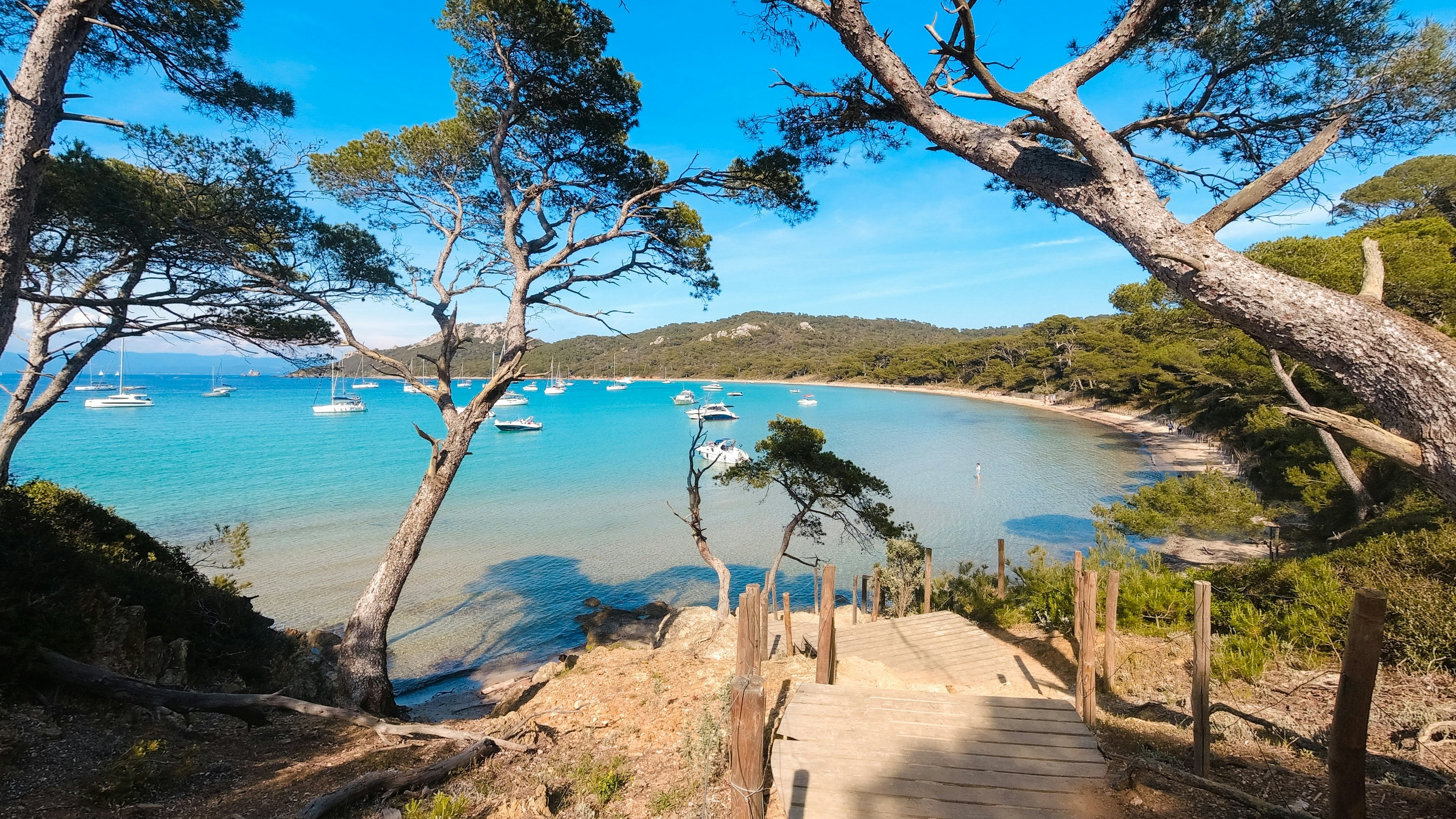 A wood pathway leads to a deep blue cove with boats.