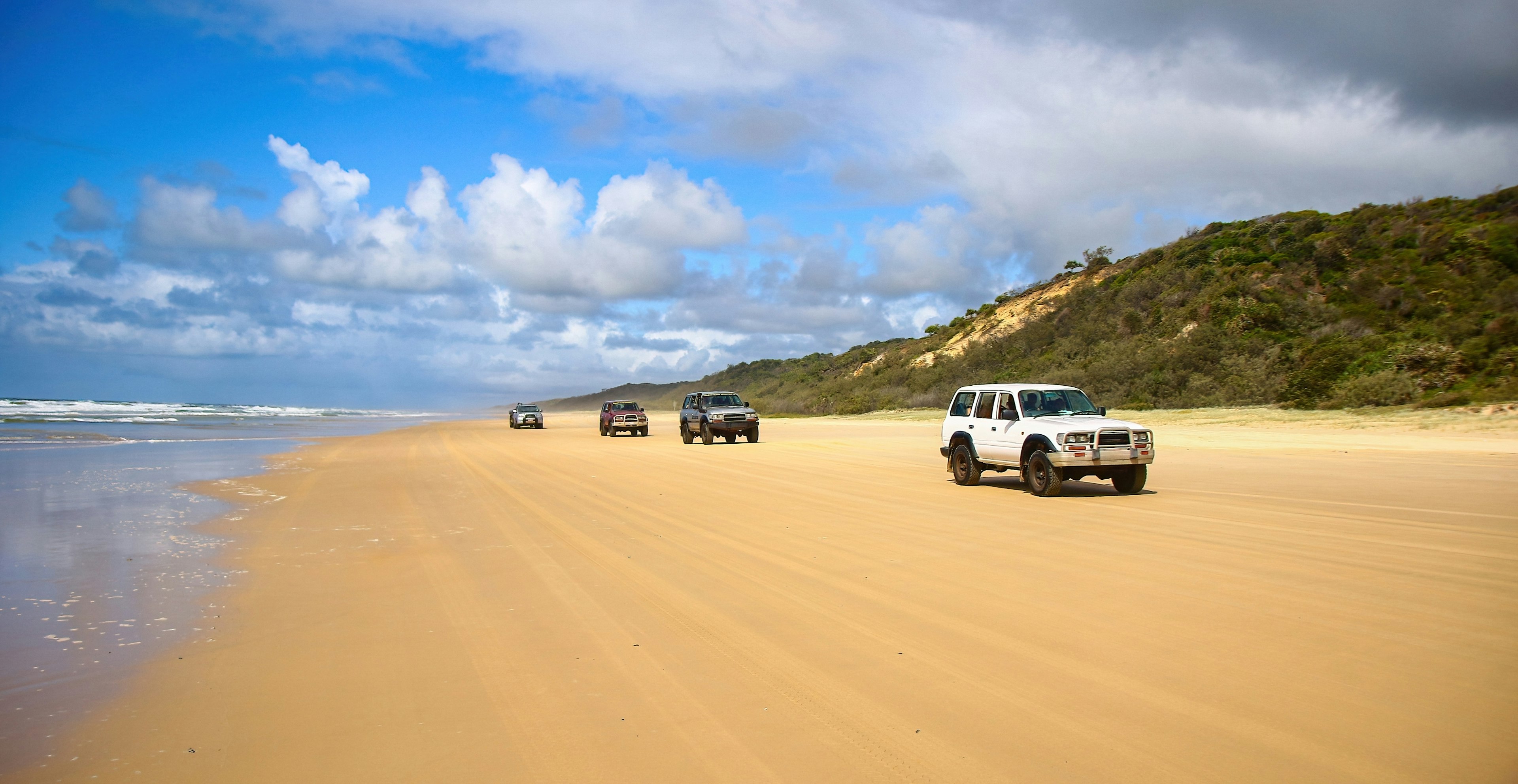 Fraser Island, Australia - March 17, 2023 : 4-wheel drive pickups travelling on the sandy highway of the 75-mile beach on the east coast of Fraser Island, Queensland, Australia