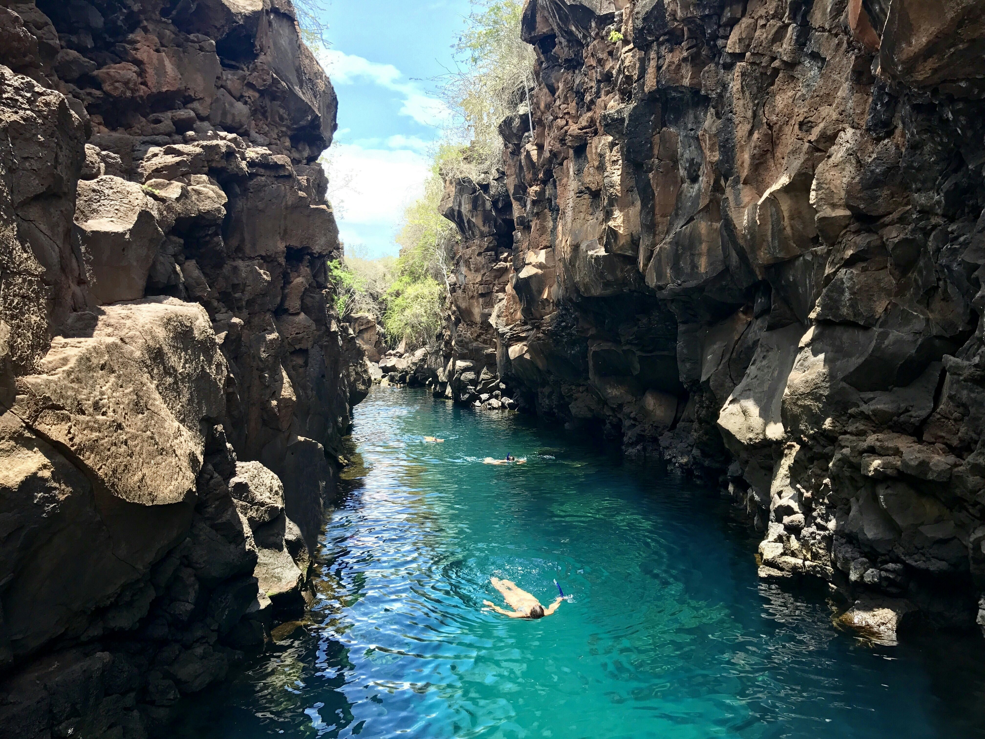 People swimming in a scenic natural pool in Santa Cruz Island, Galápagos, Ecuador.