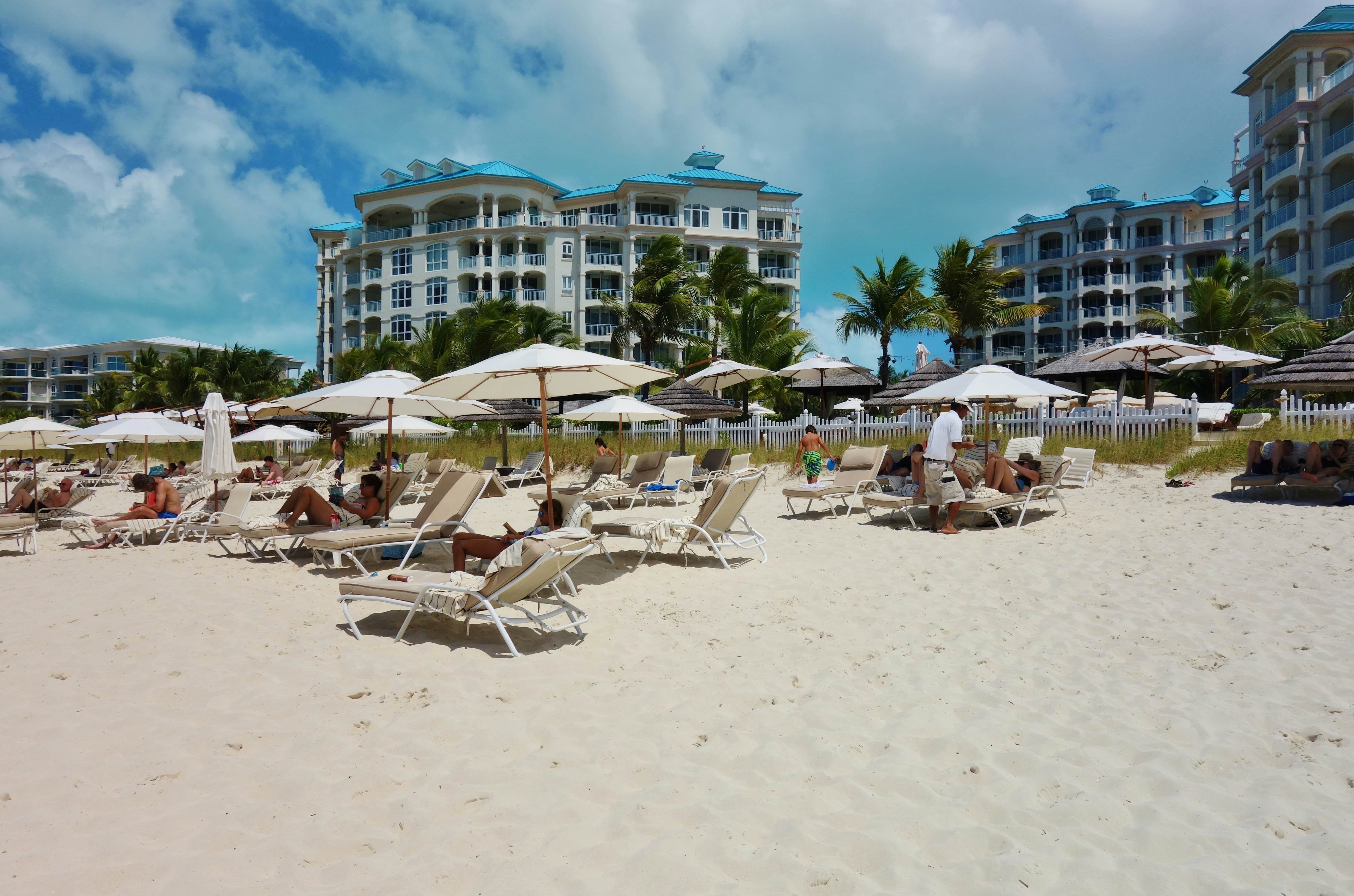 People sit under umbrellas at Grace Bay Beach, a landmark azure beach in Provo in the Turks and Caicos Islands.