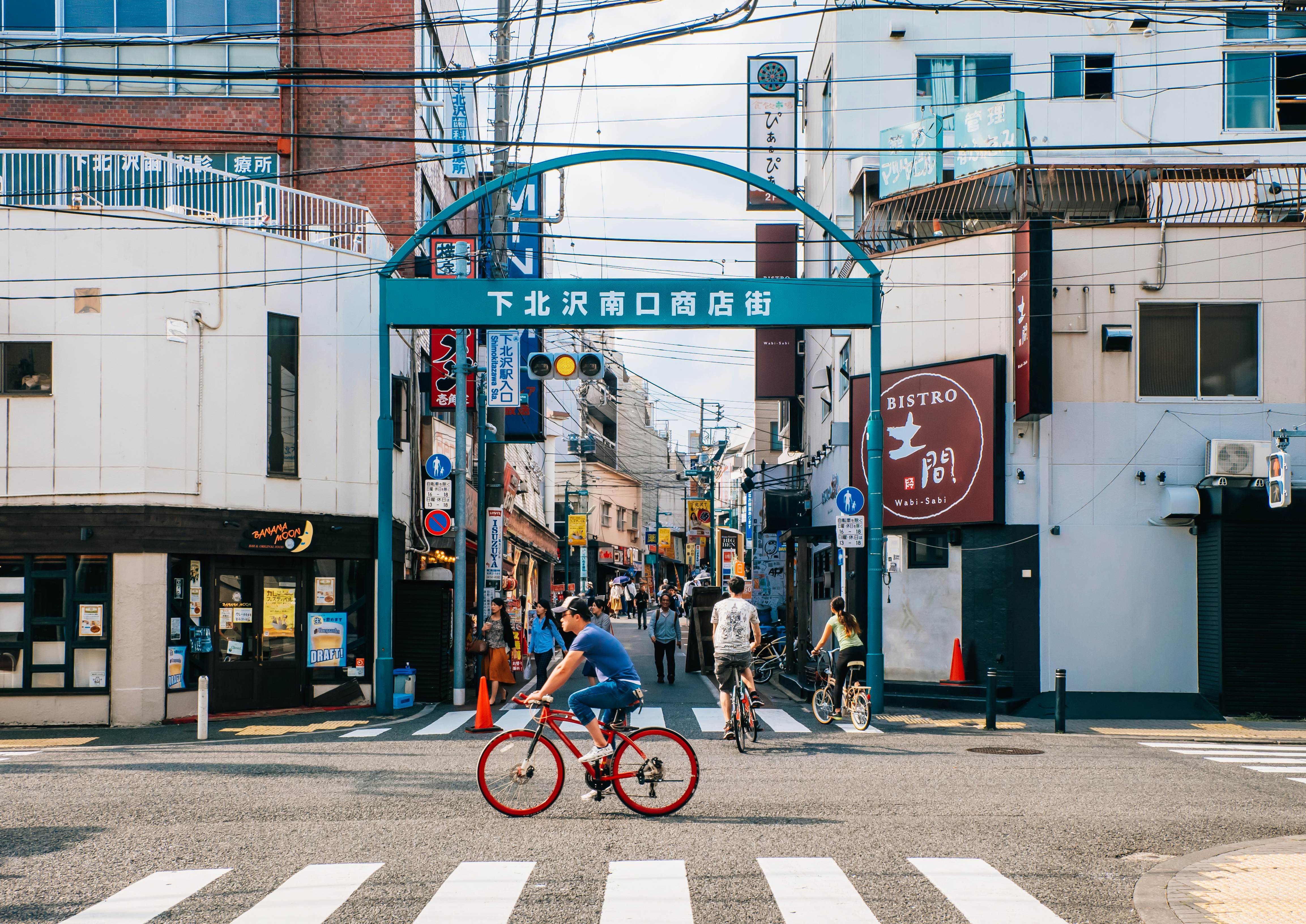 People riding bikes and wandering through the streets of a neighborhood in Tokyo