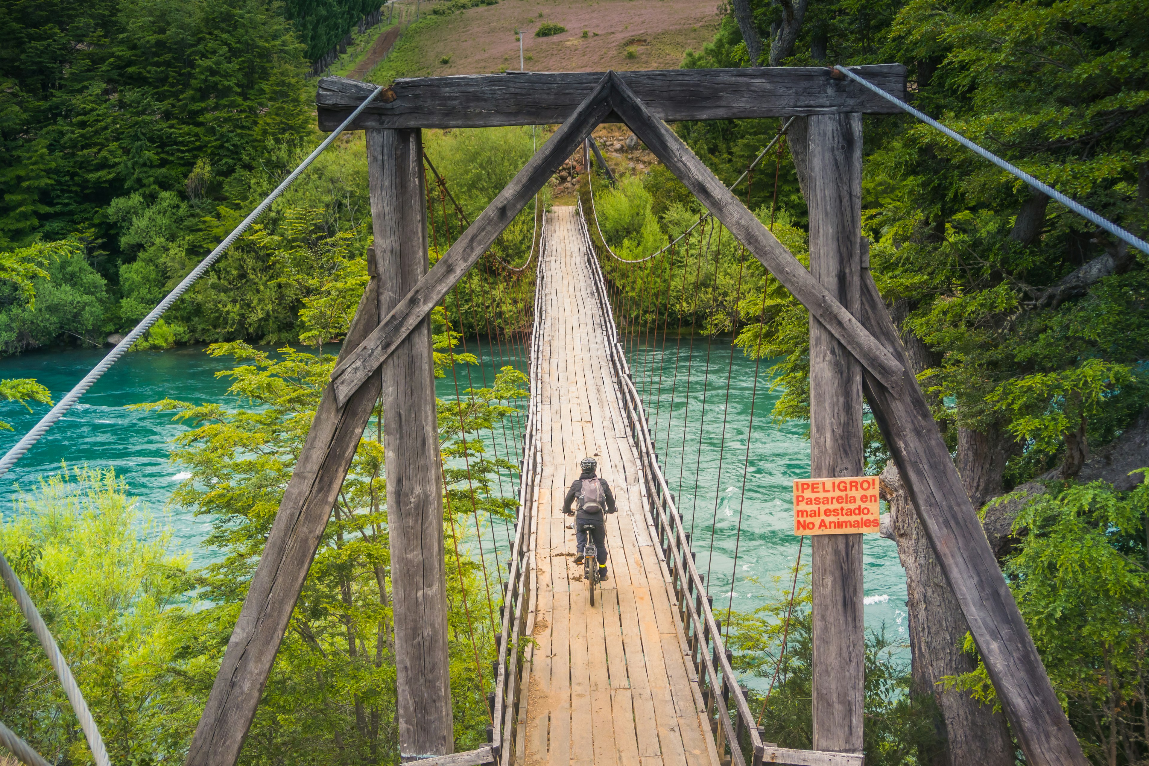 Person on a bicycle crosses a wooden bridge at Futaleufu, Patagonia in Chile.