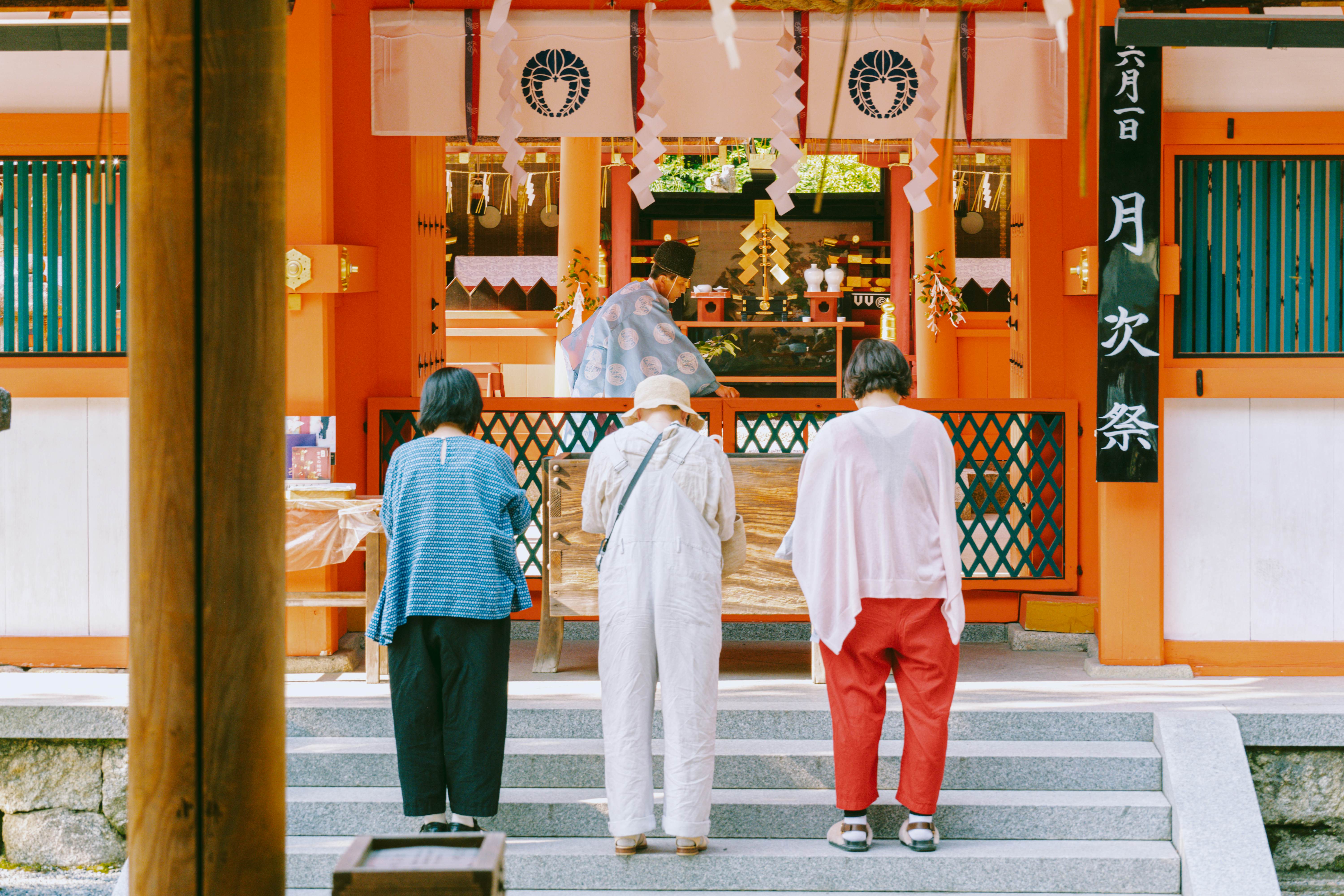 Three women wait on steps outside a tea shop at a market.