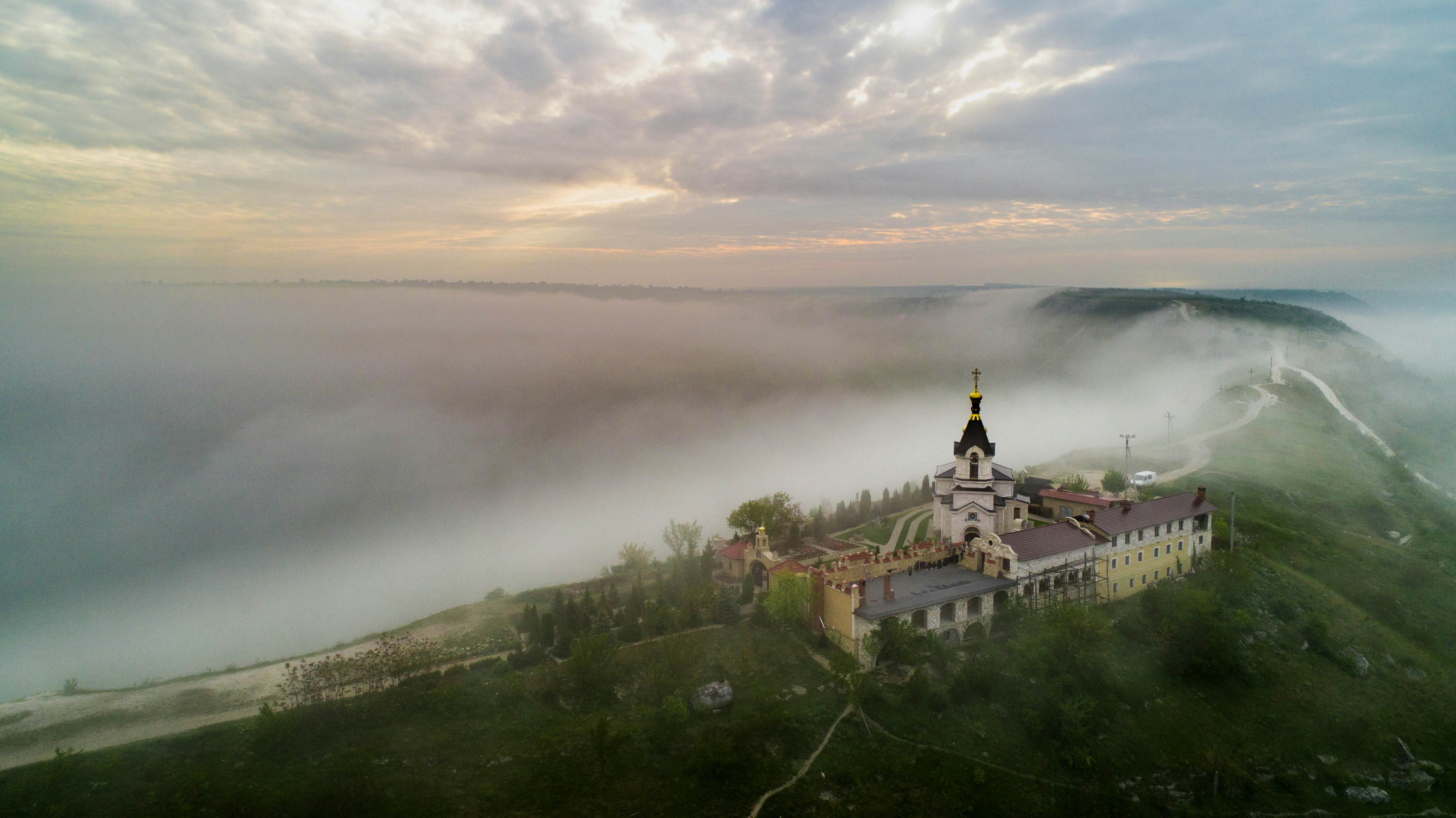 A church on the ridge of a hill as fog sweeps in from the valley below