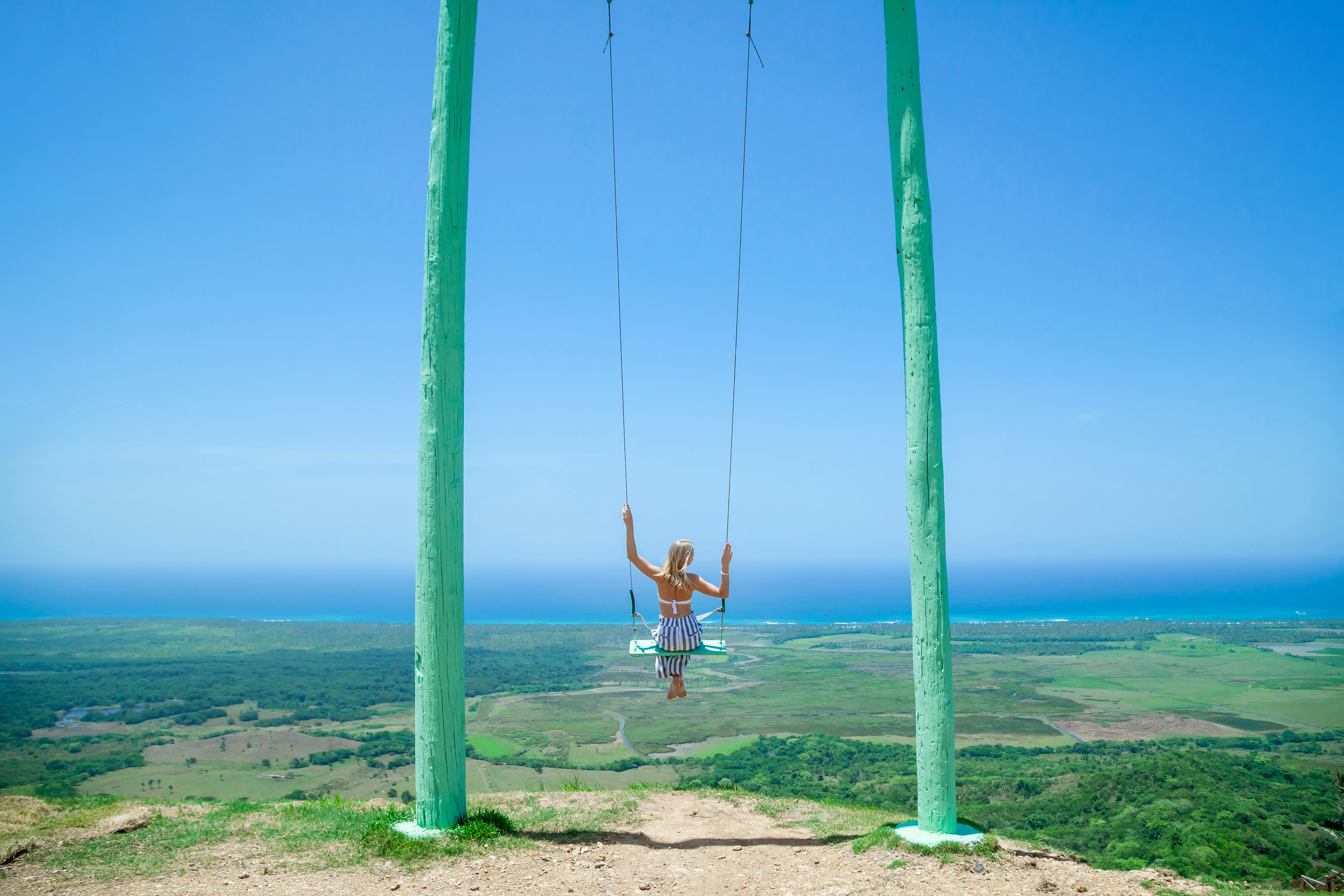 Woman swinging on a swing in front of the view at Montana Redonda, Dominican Republic.