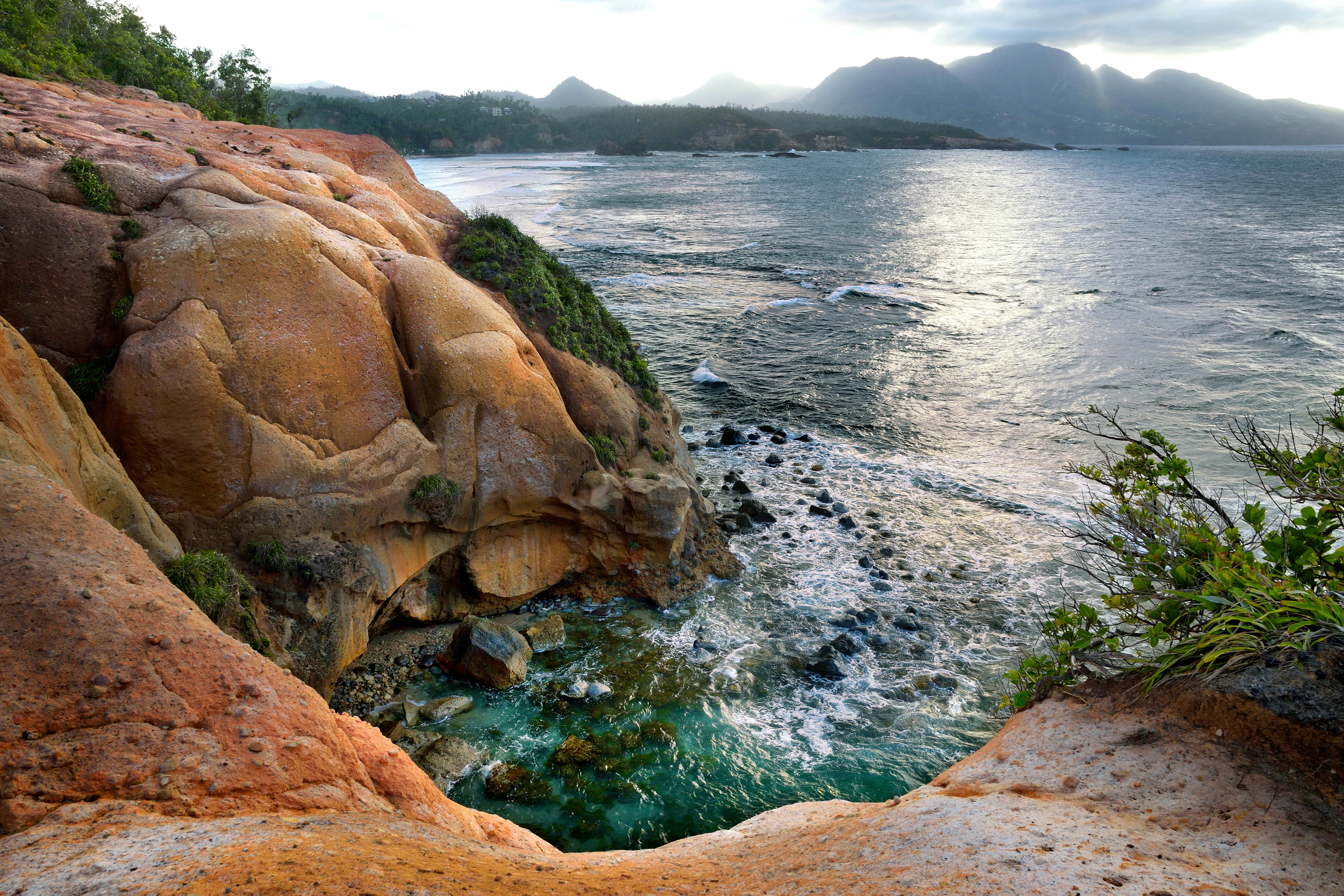 Waves crash against unusual rust-colored coastal cliffs