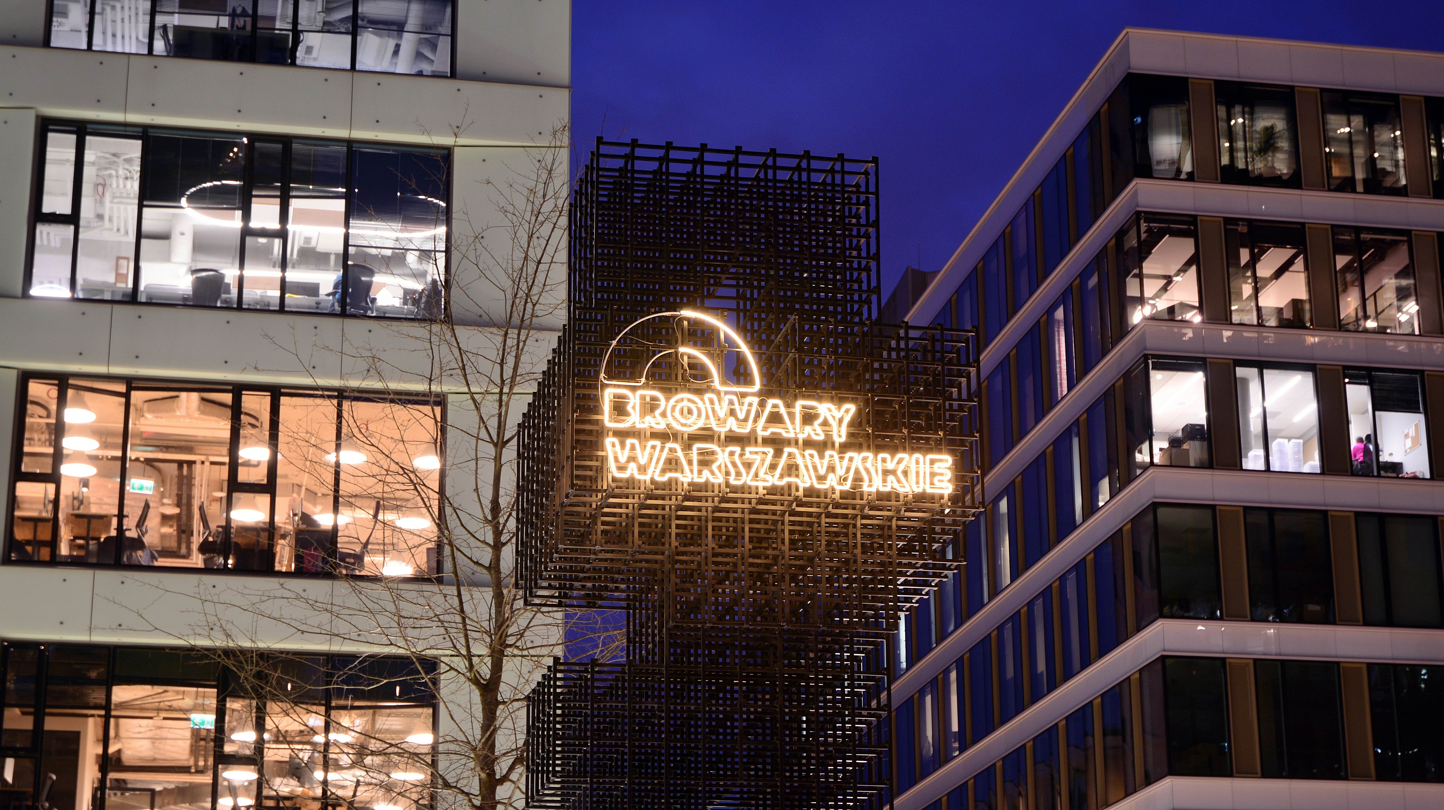 The exterior of an entertainment district at night, with a lit-up sign that says 