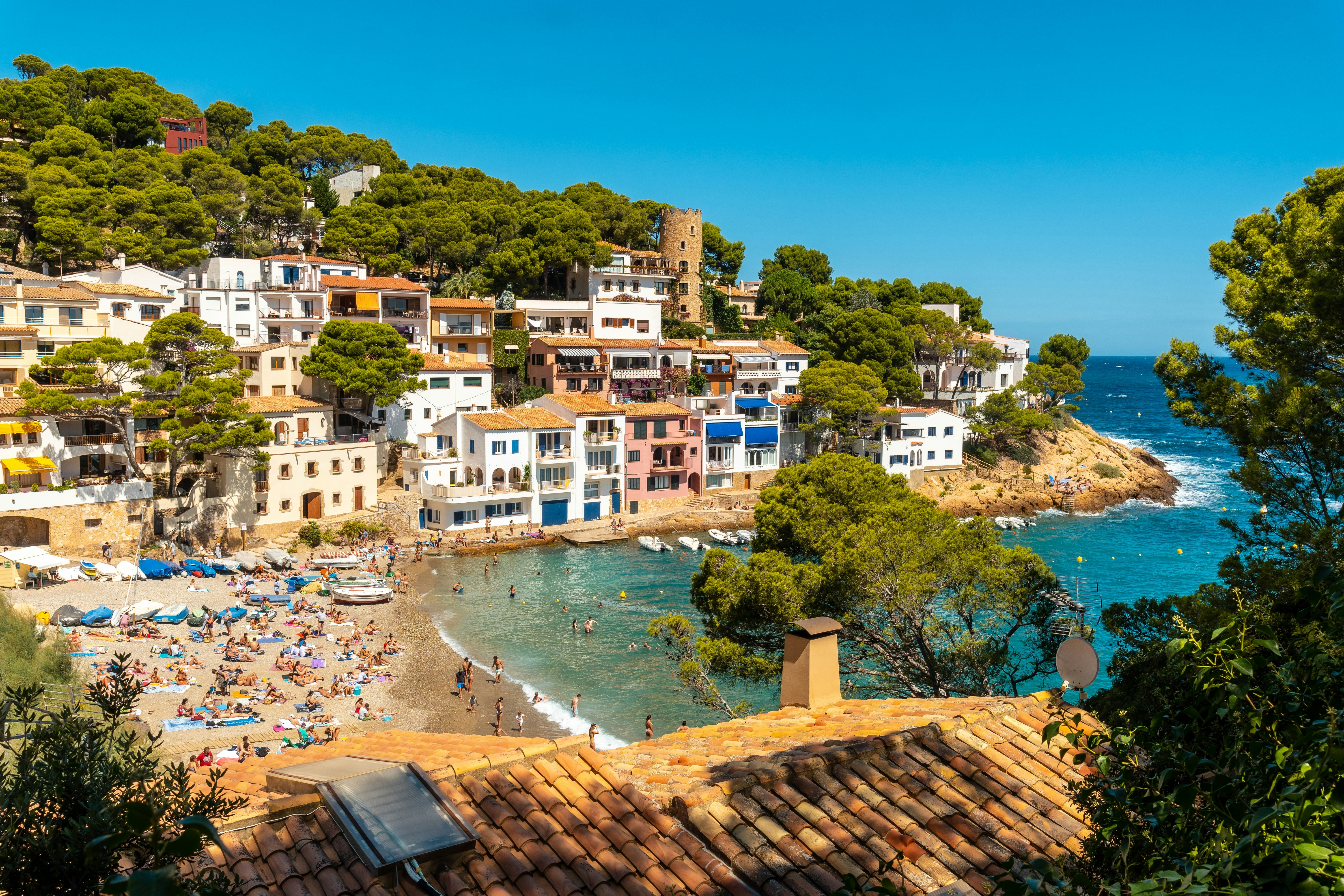 A small cove backed by apartment buildings and lined with sunbathers and swimmers.