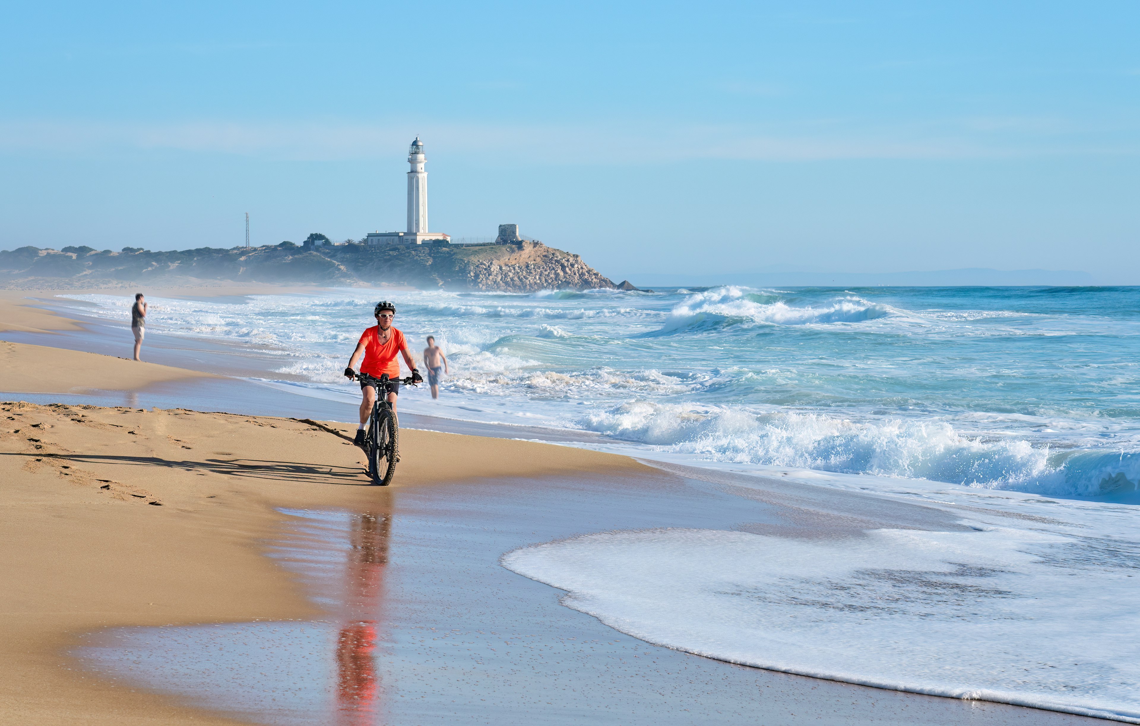 A woman riding a mountain bike on the sand on the Costa de la Luz, Andalucia, Spain.