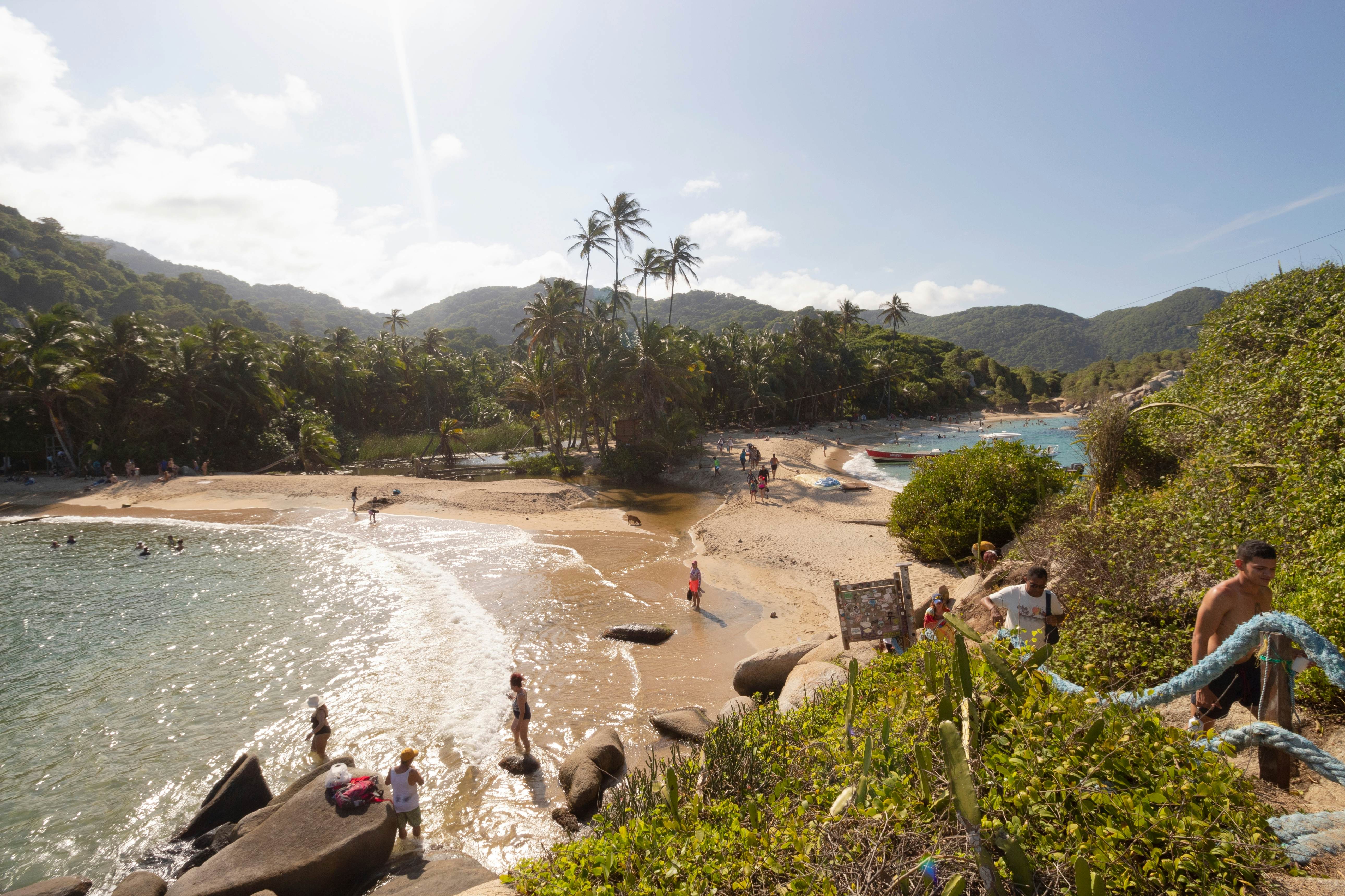 A view of a cove with a beach. People are seen on the beach, and climbing steps that lead away from the sand.