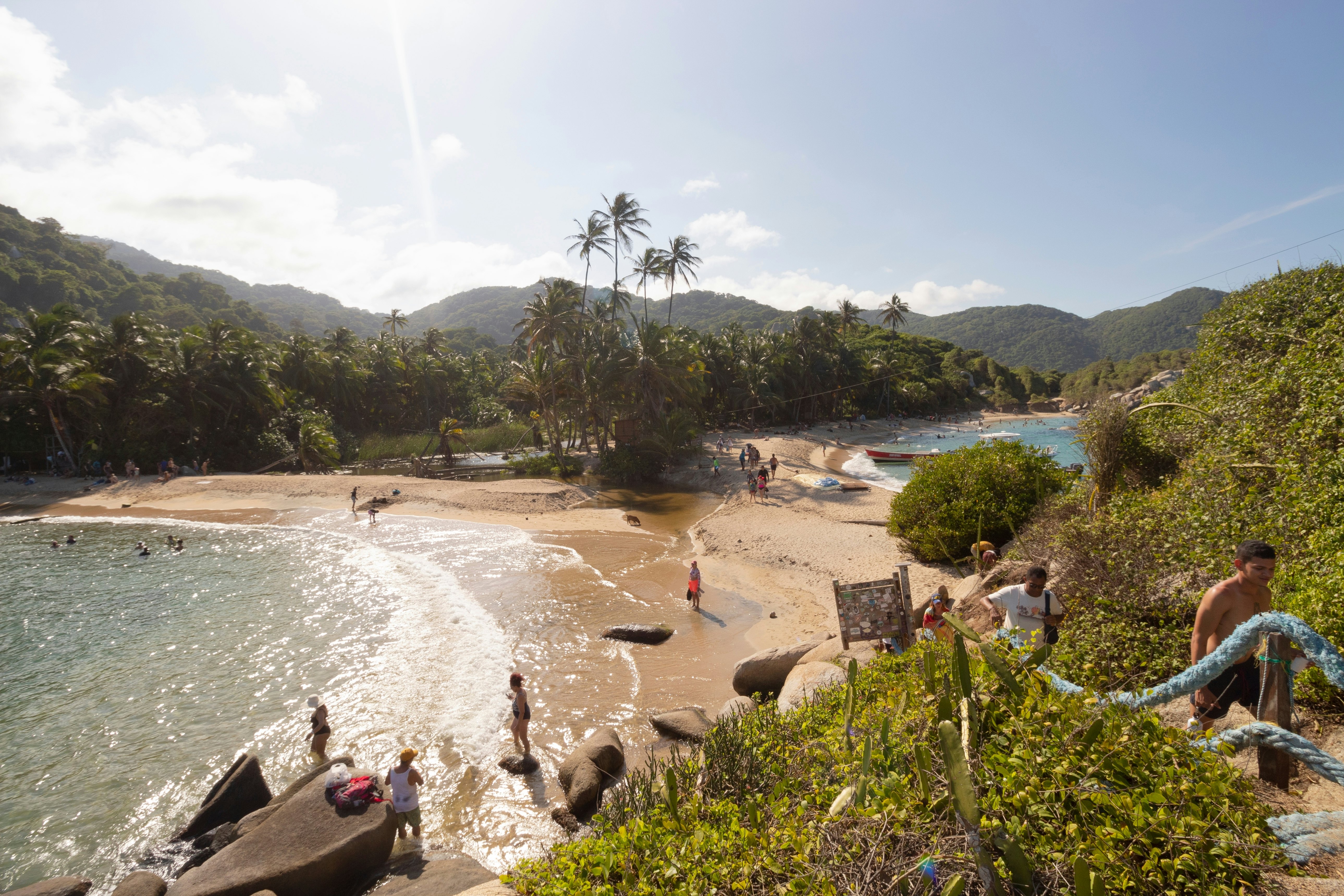 A view of a cove with a beach. People are seen on the beach, and climbing steps that lead away from the sand.