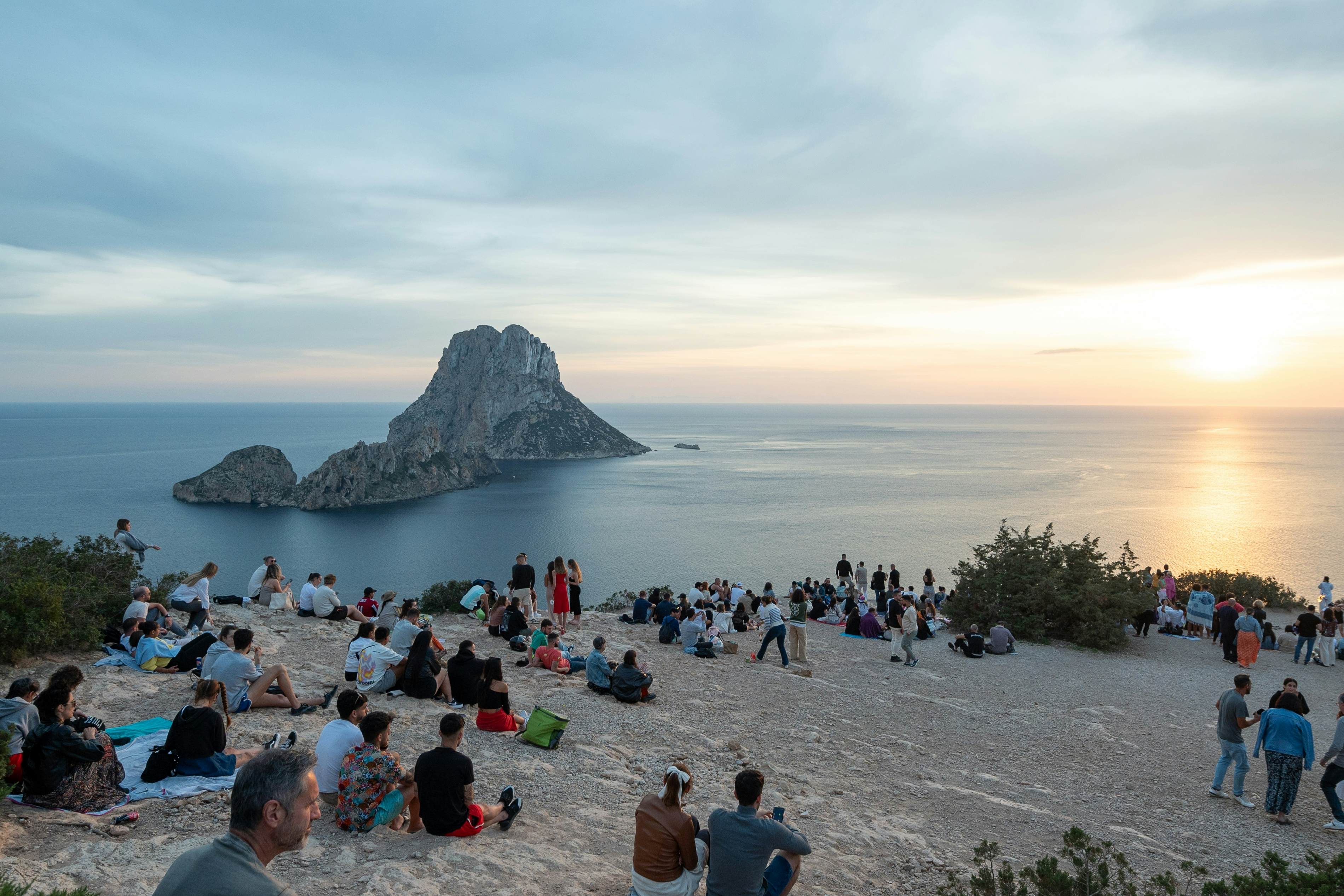 People enjoying the sunset at the Es Vedra viewpoint in Ibiza in summer.