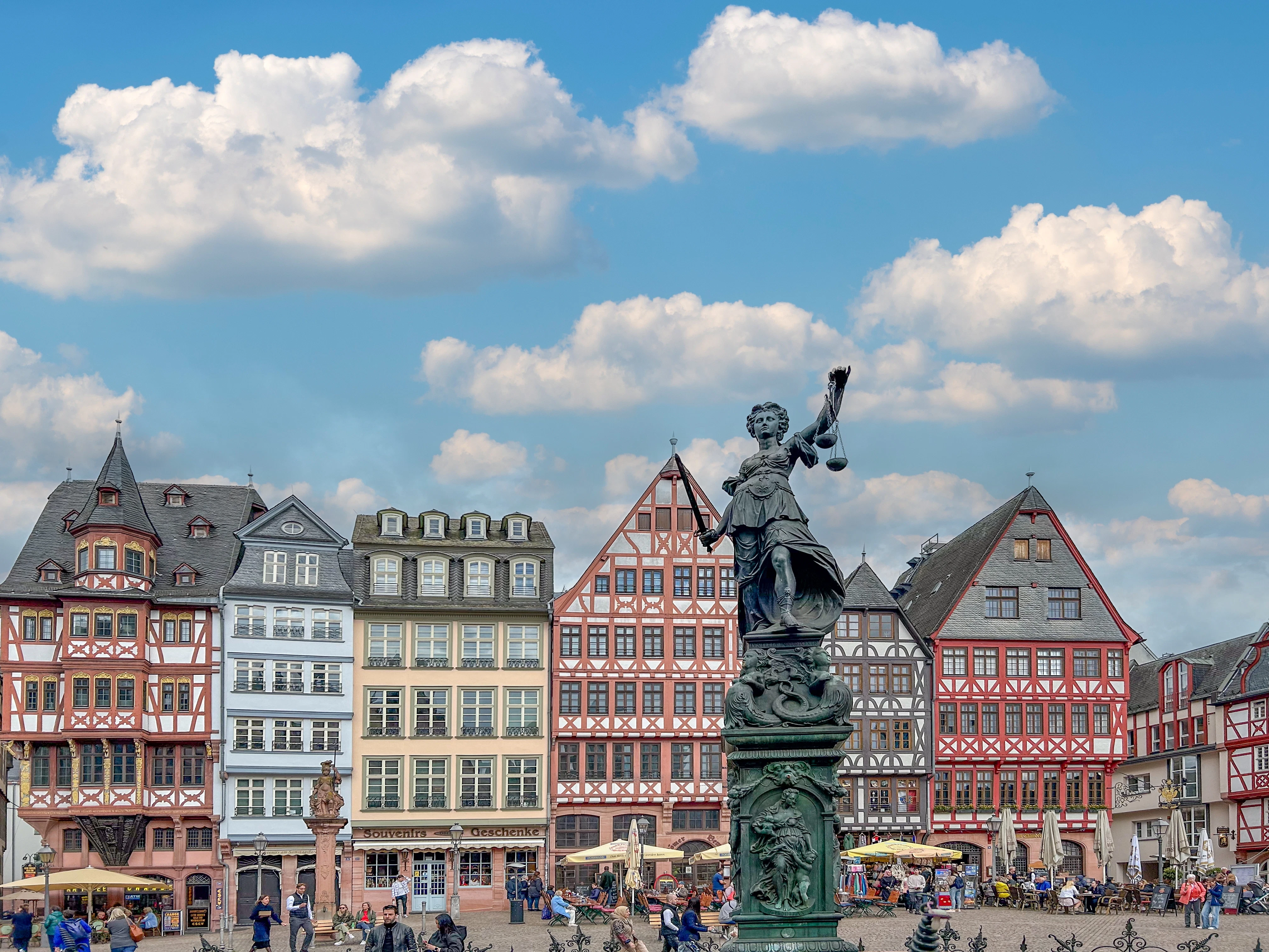 Frankfurt, Germany - April 10, 2024: people walking at the Roemer square, the old central market square with statue of Lady Justice in Frankfurt.