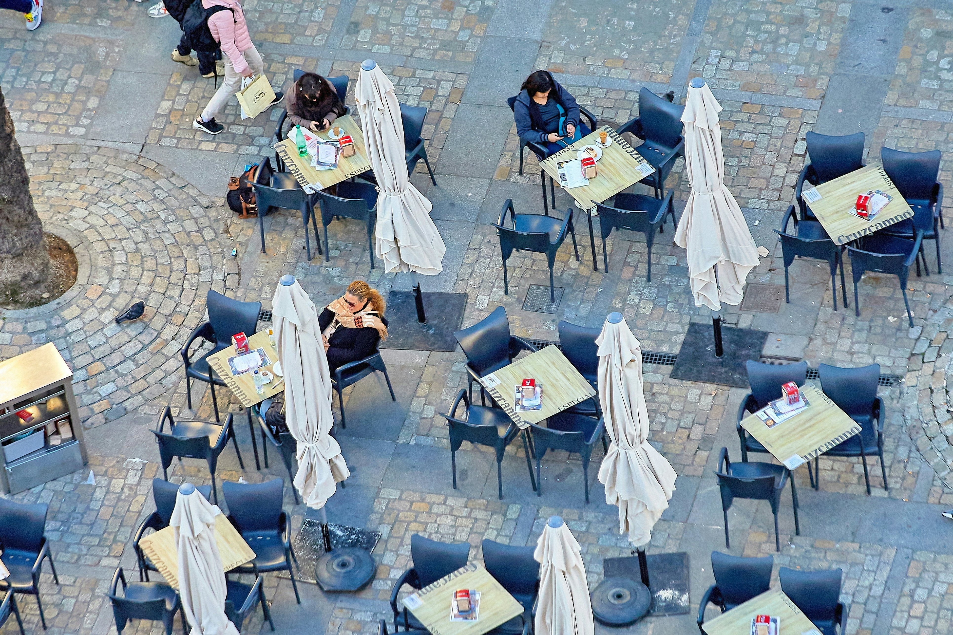 Tables, chairs and umbrellas of a cafe in a city square.