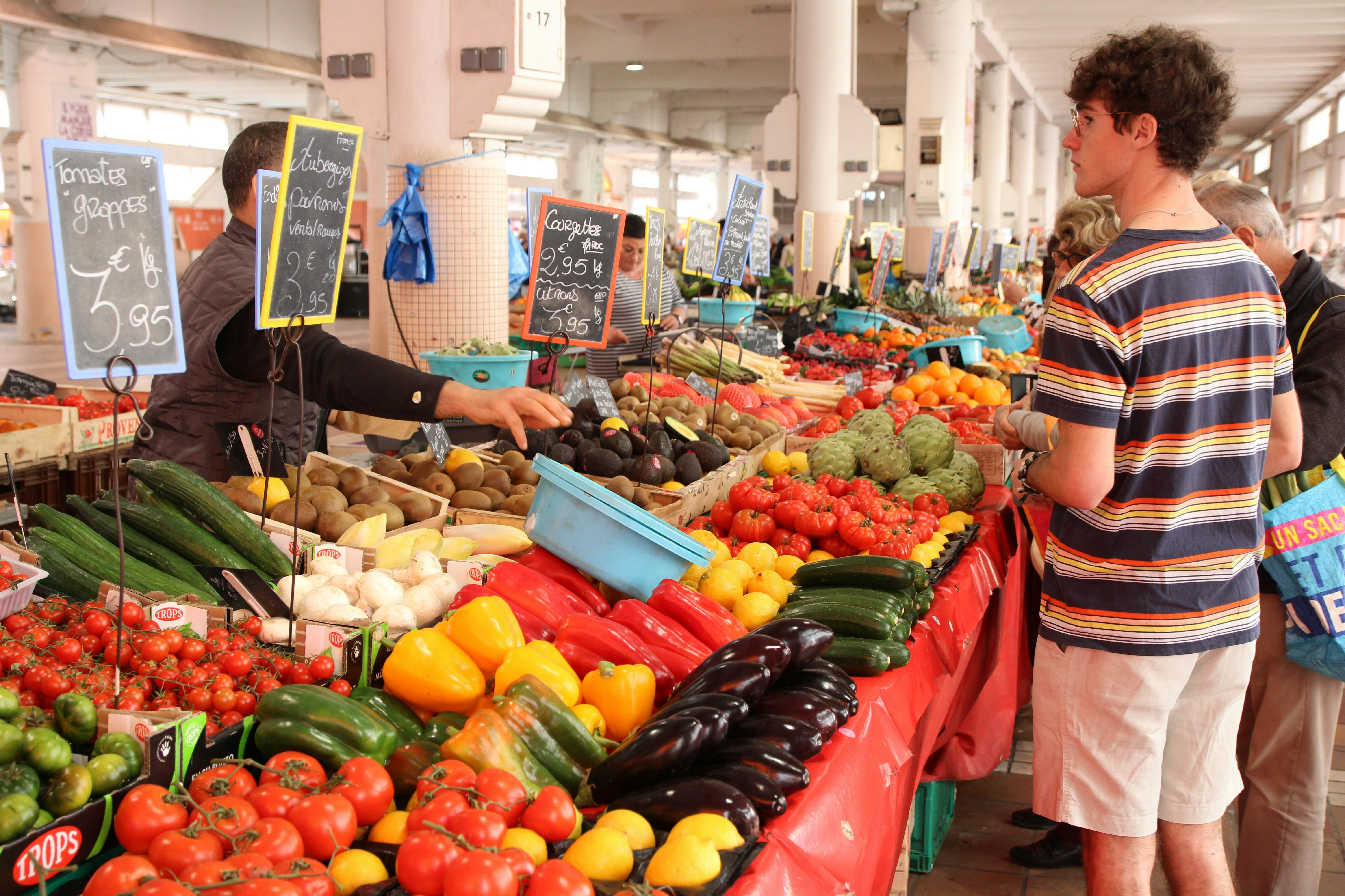 A male customer shops for peppers, zucchini, artichokes and other fresh produce at an indoor market.