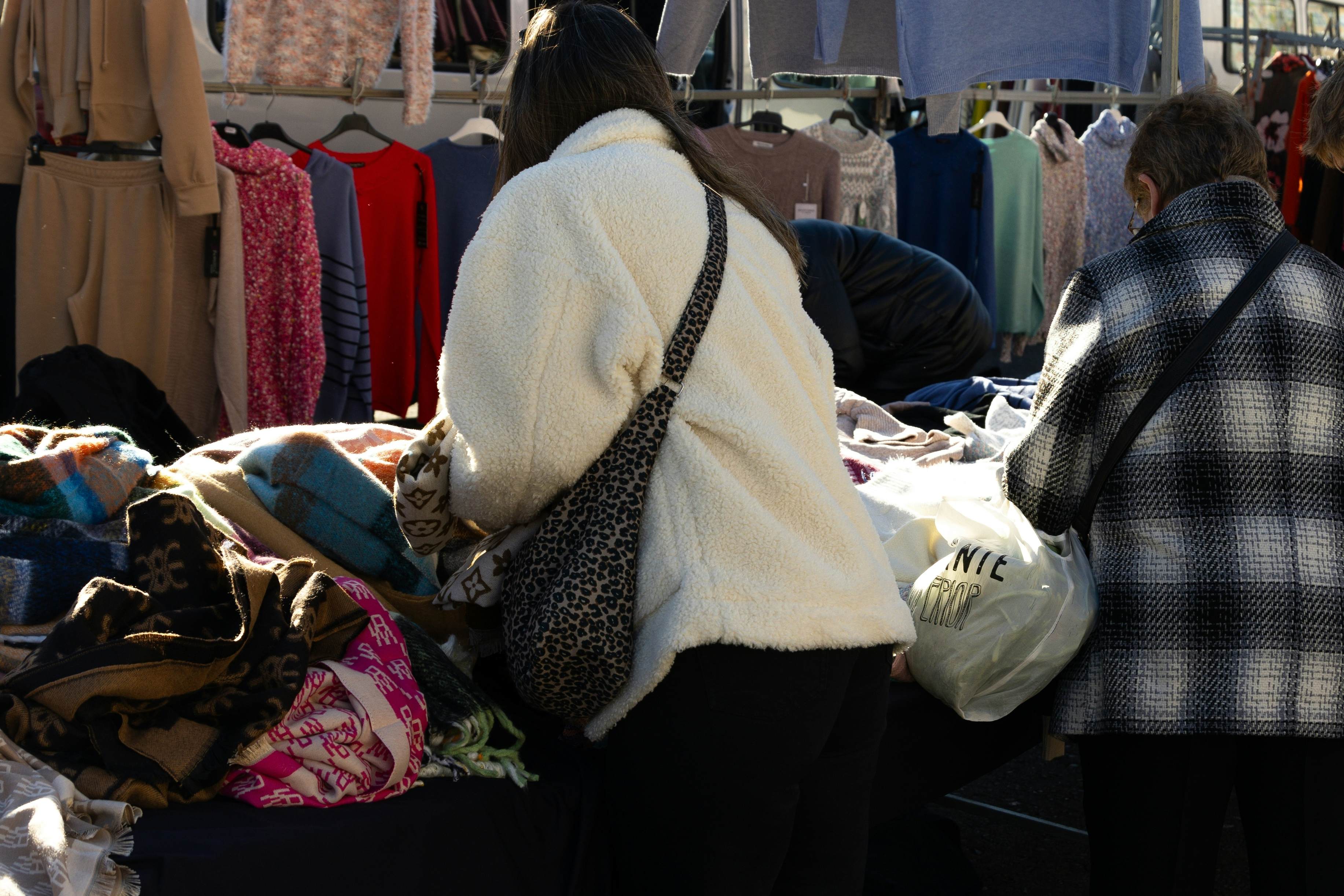 Women rummaging through piles of clothing at an outdoor market in Vigo.