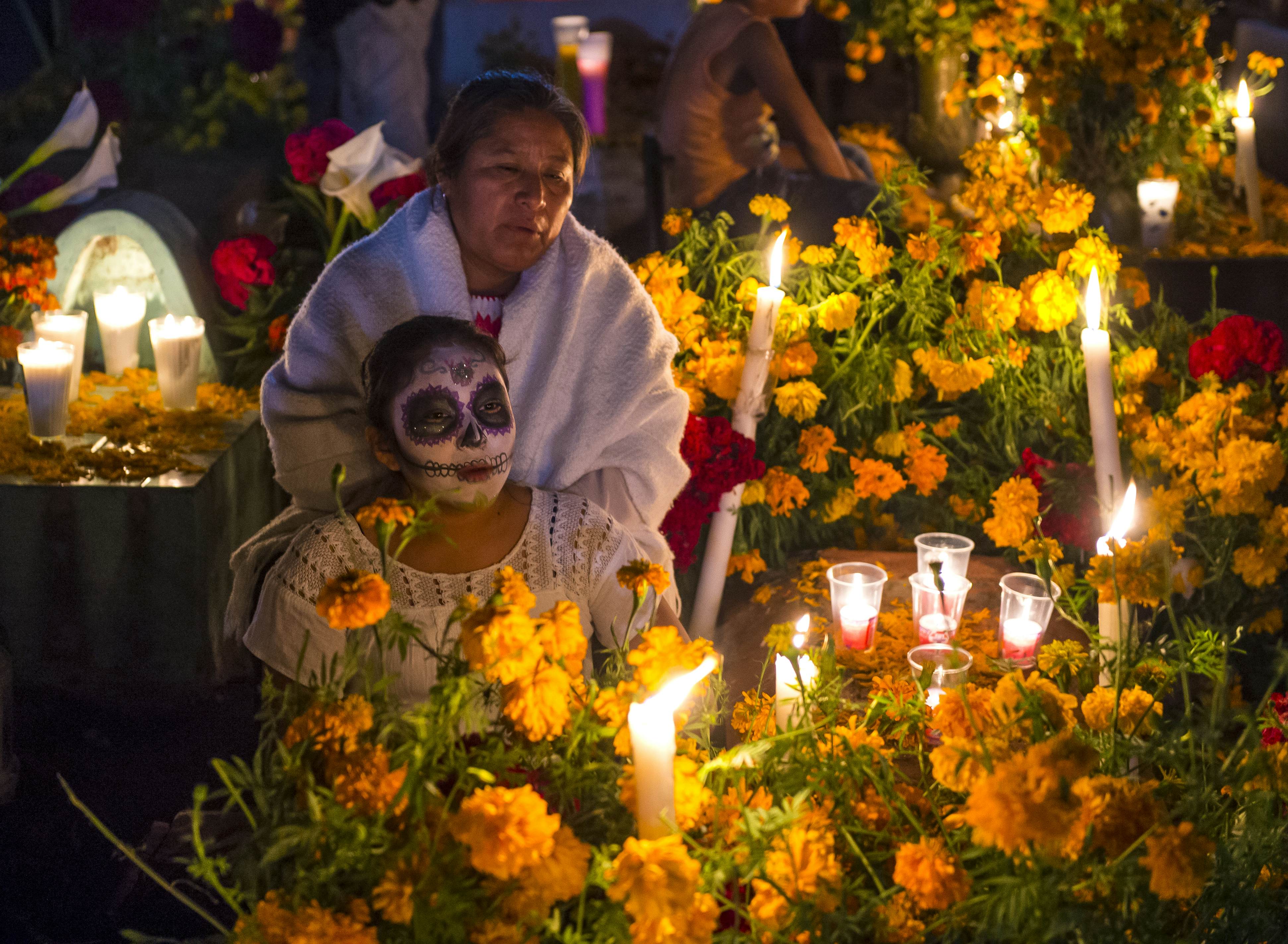 A Mexican family at a memorial in a cemetery during the Day of the Dead in Oaxaca, Mexico.