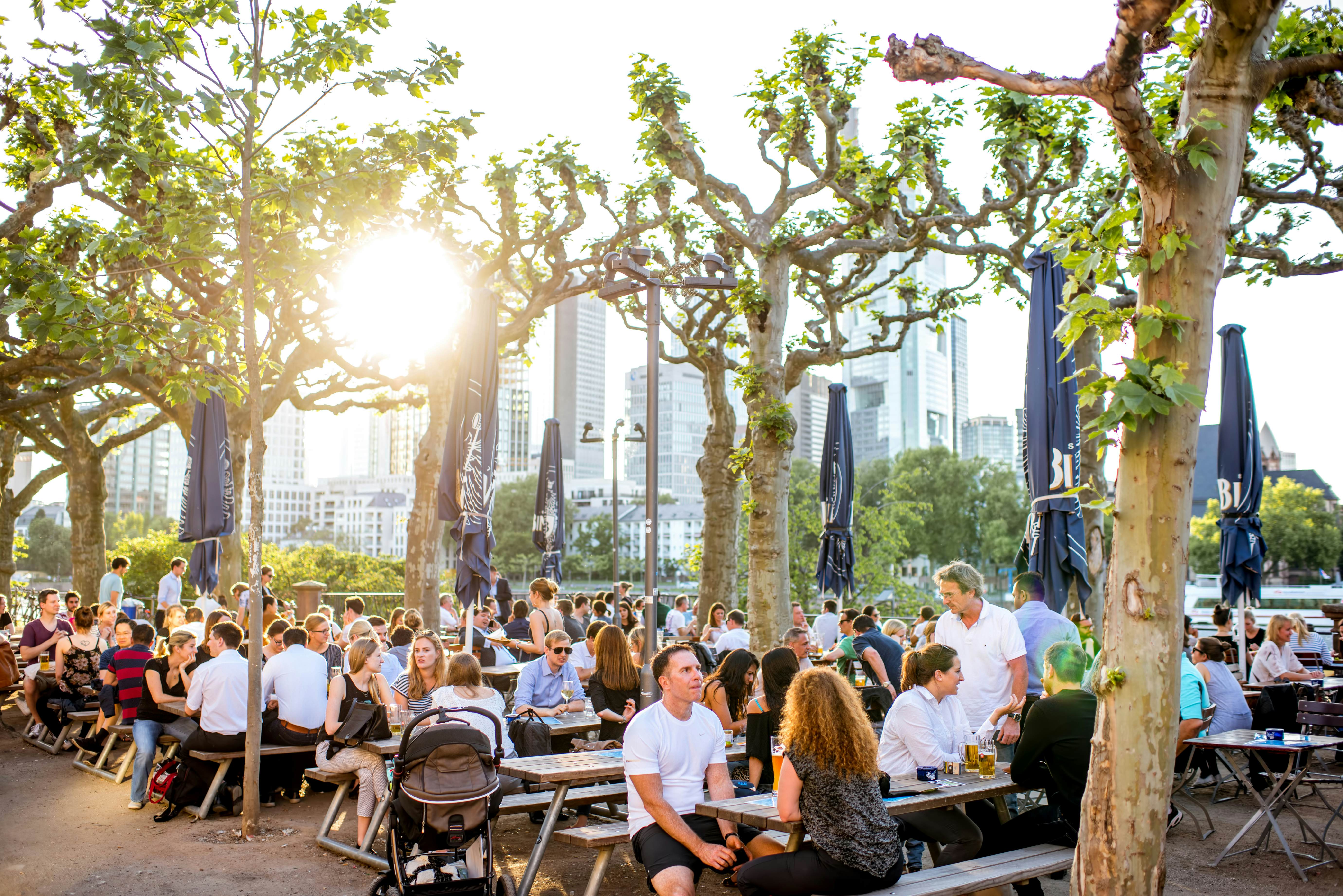 FRANKFURT, GERMANY - May 16, 2017: People sitting at the bar in the park near the Iron bridge with great view on the financial district in Frankfurt city.