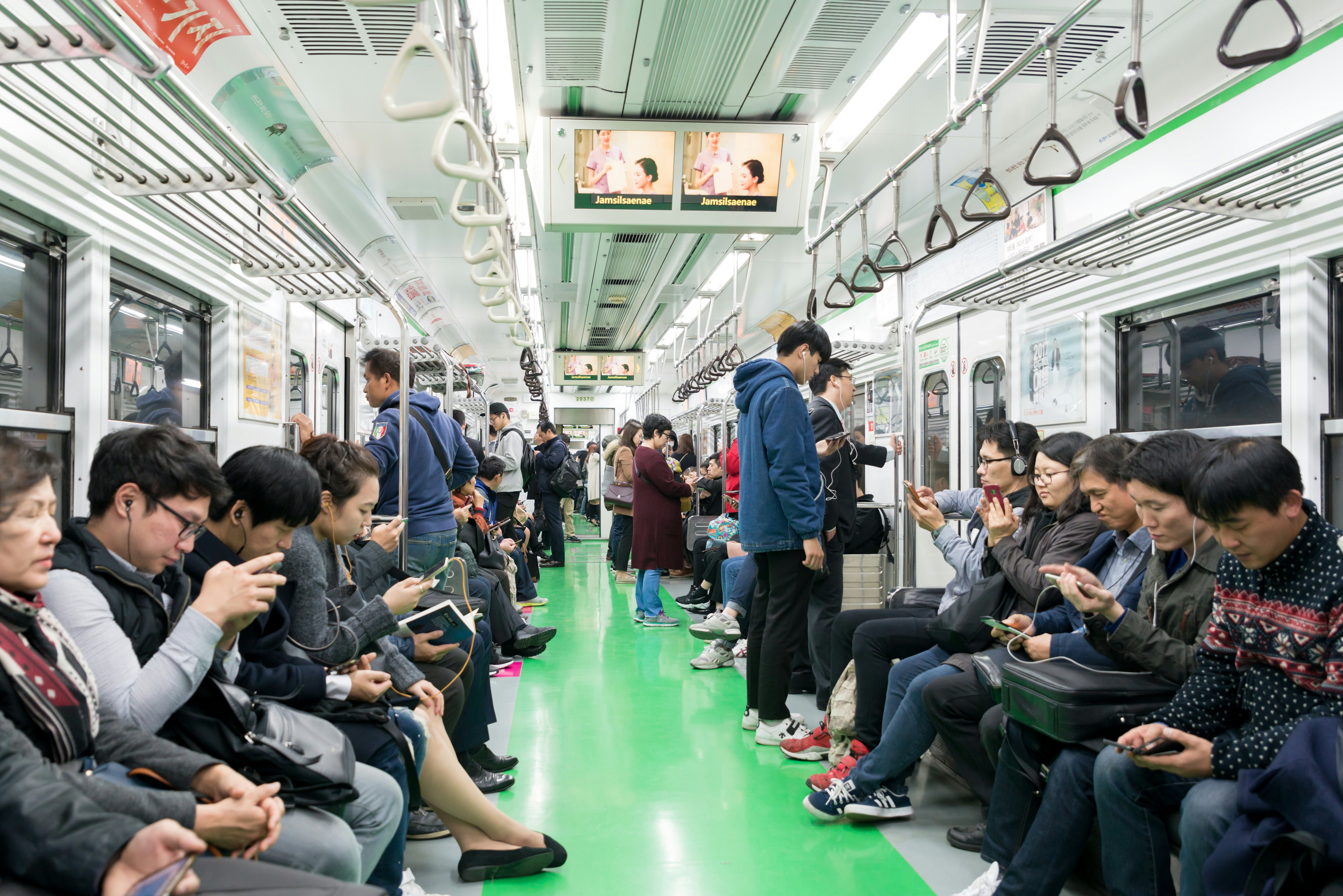 Passengers are pictured inside a metro car. While there are many people in the seats, the car is only partially full.