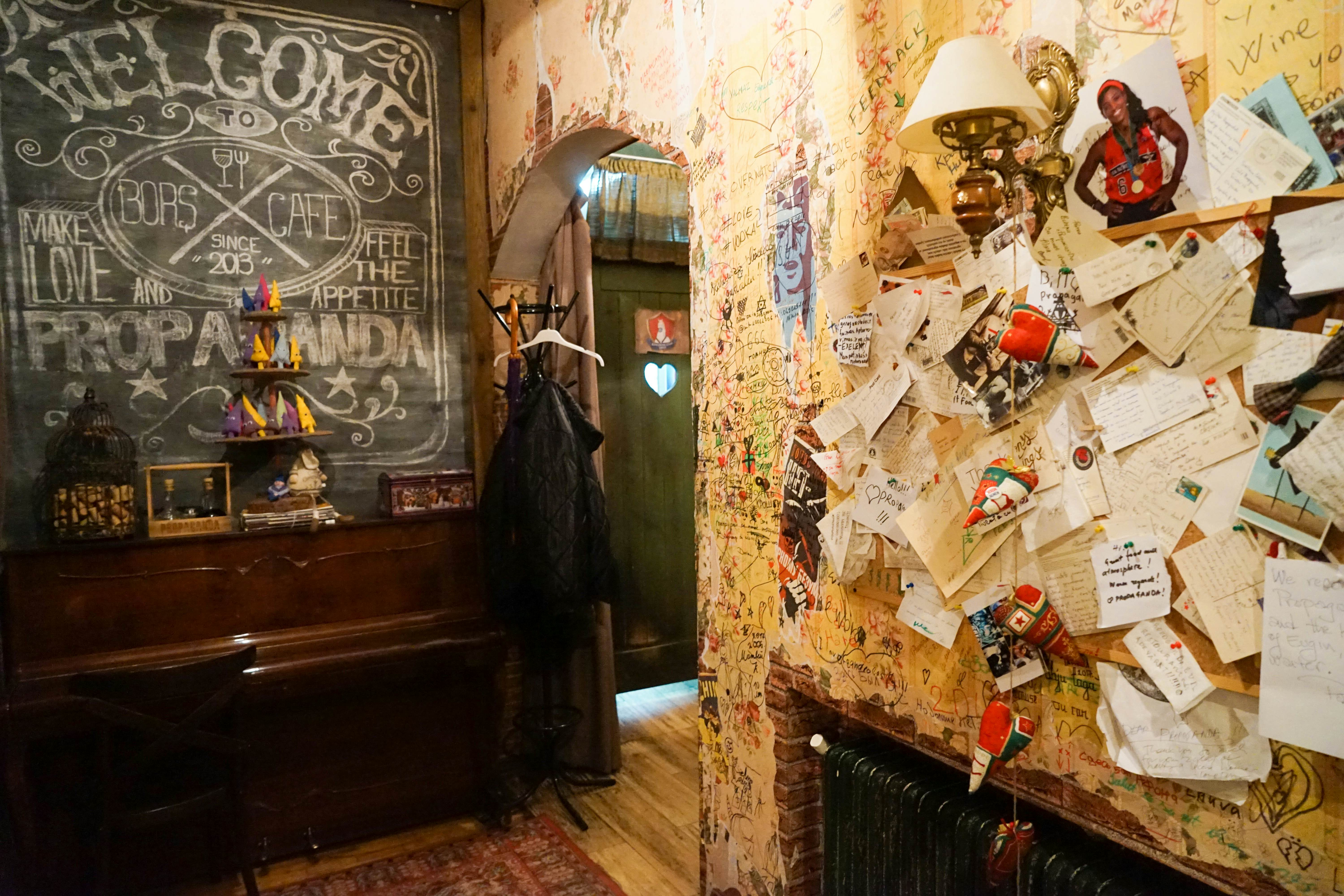 Interior of a cafe with notes scribbled all over the walls and some stuck to a noticeboard