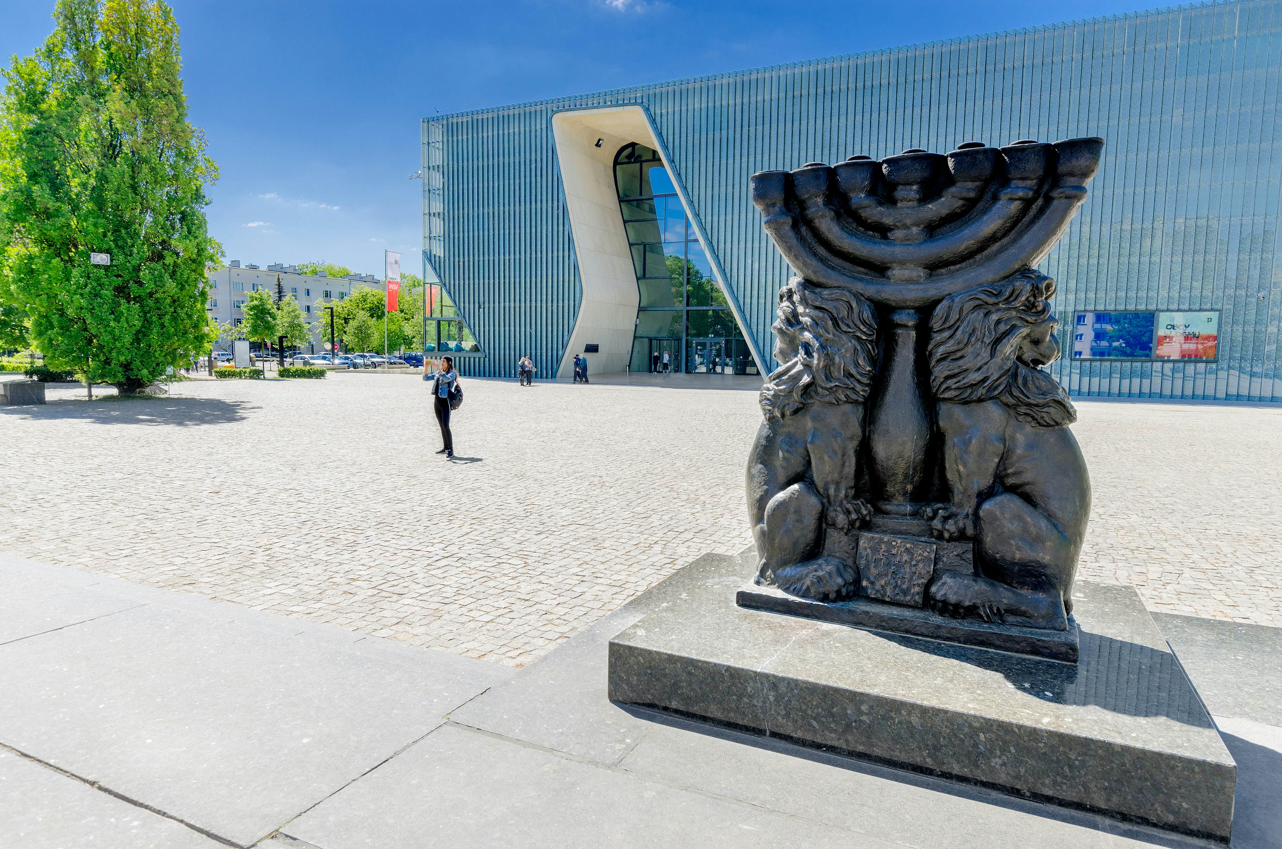 A black sculpture of two lions either side of a menorah in the square outside a museum