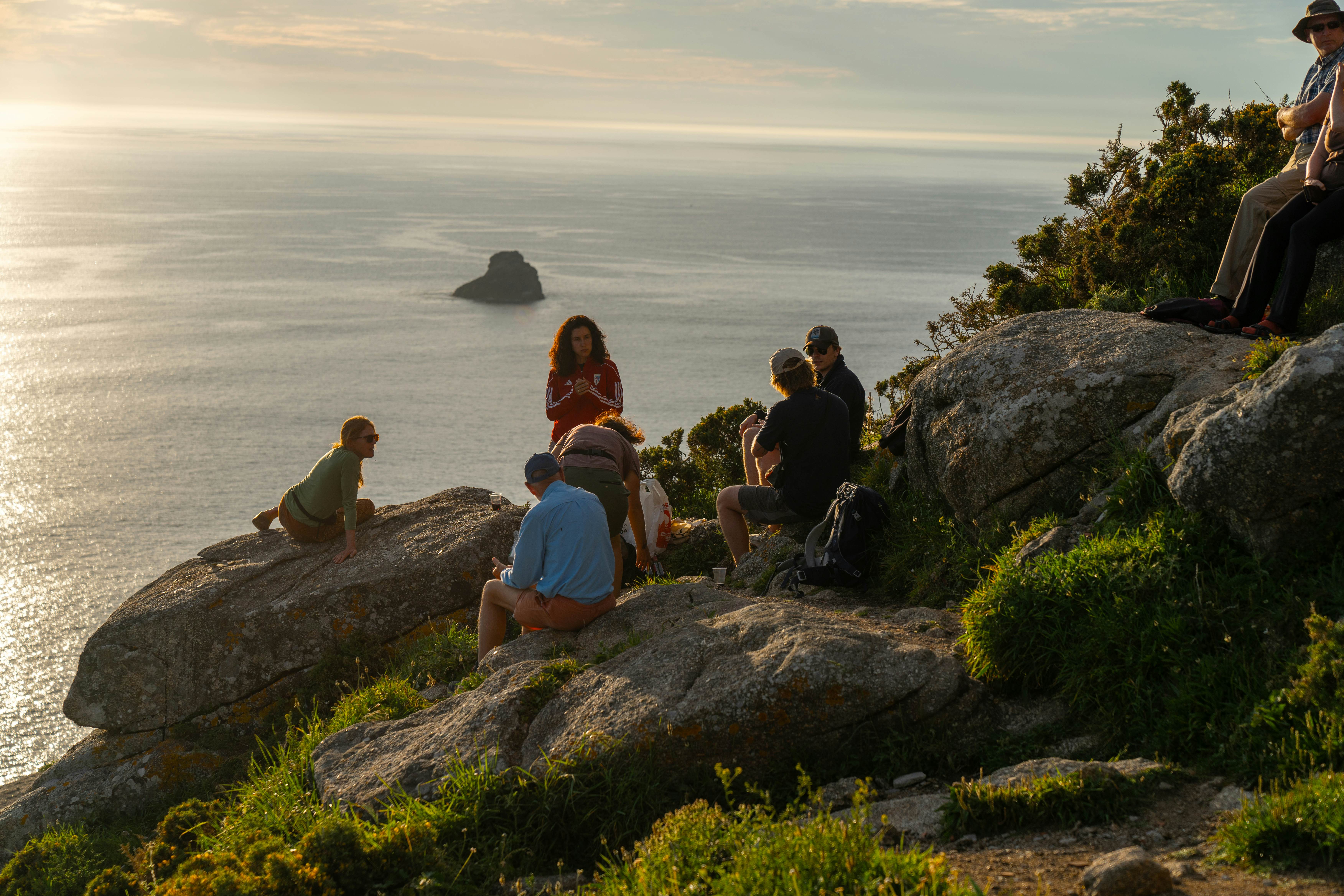 People gather at sunset on the cliffs of Finisterre