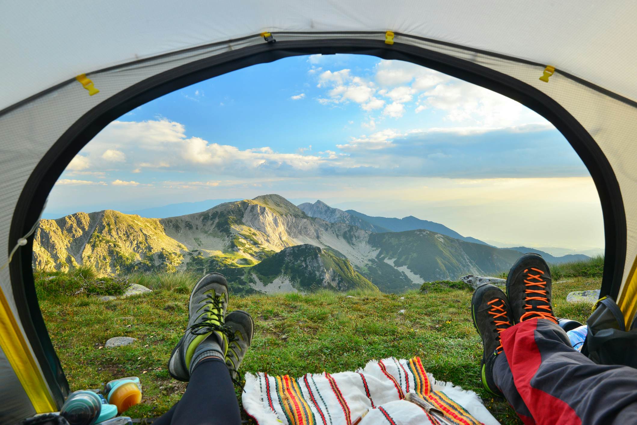 Hikers looking through tent door at mountains in Pirin National Park, Bulgaria.