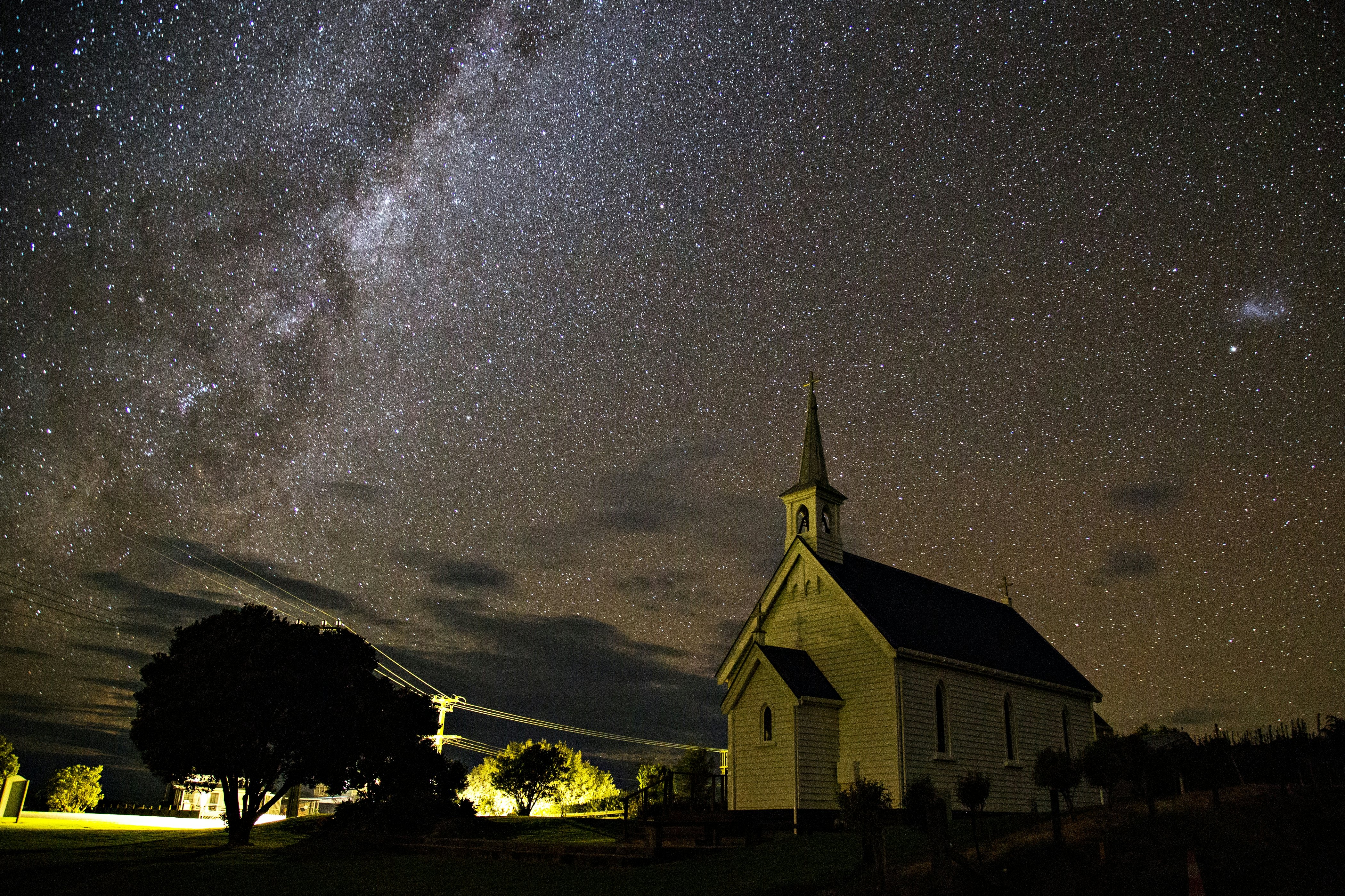 A small village church at night with a blanket of stars in the sky above