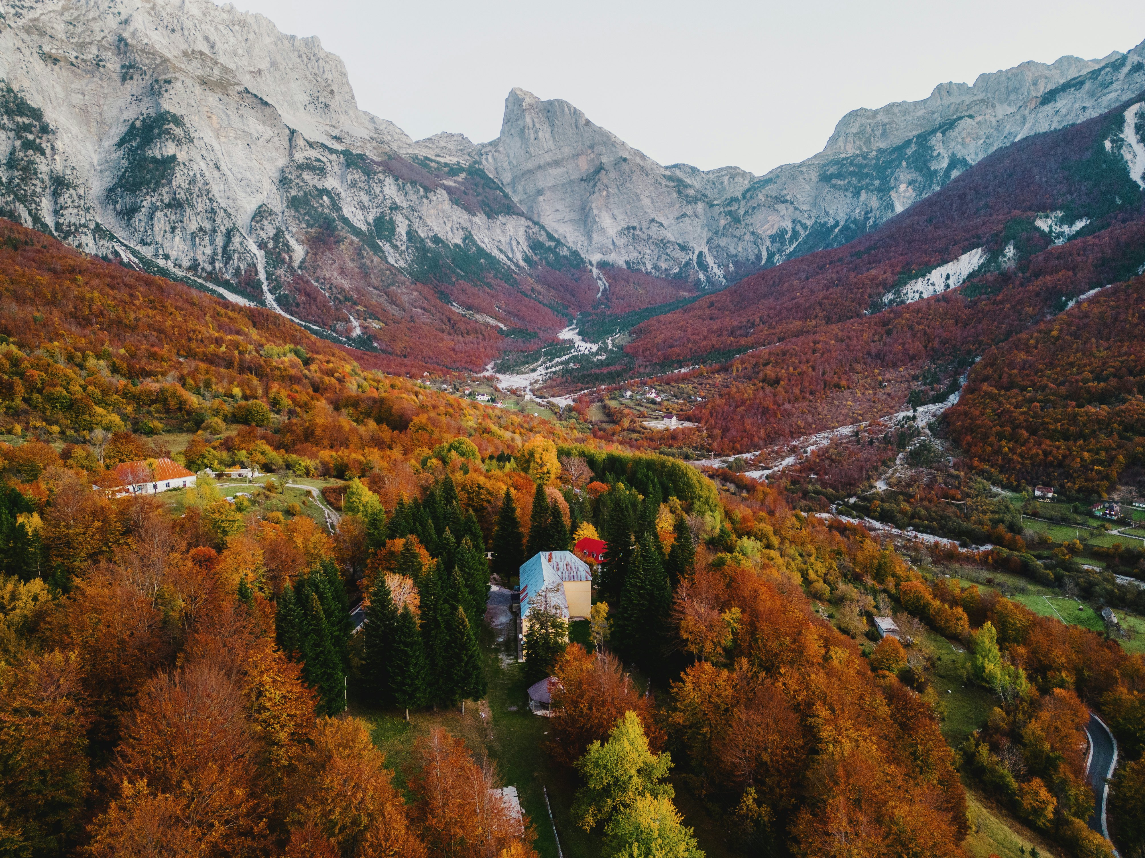 A mountain town surrounded by trees changing into oranges, golds and yellow during autumn