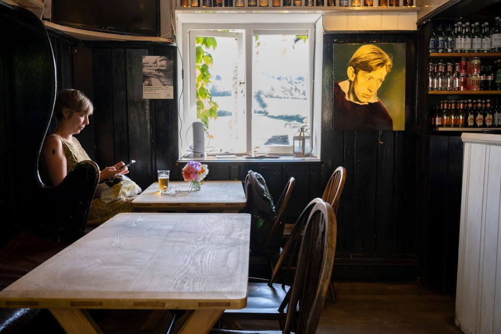 A woman drinks a beer in a booth at The Woolpack Inn, a Gloucestershire pub