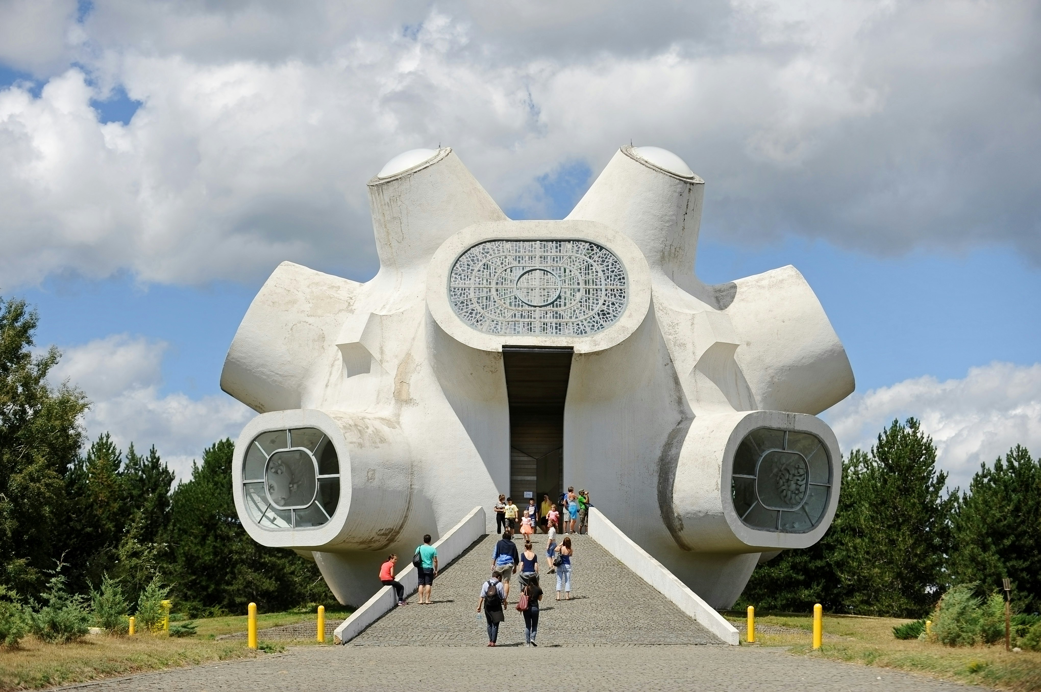 People walk towards a bulbous white monument with large projecting windows