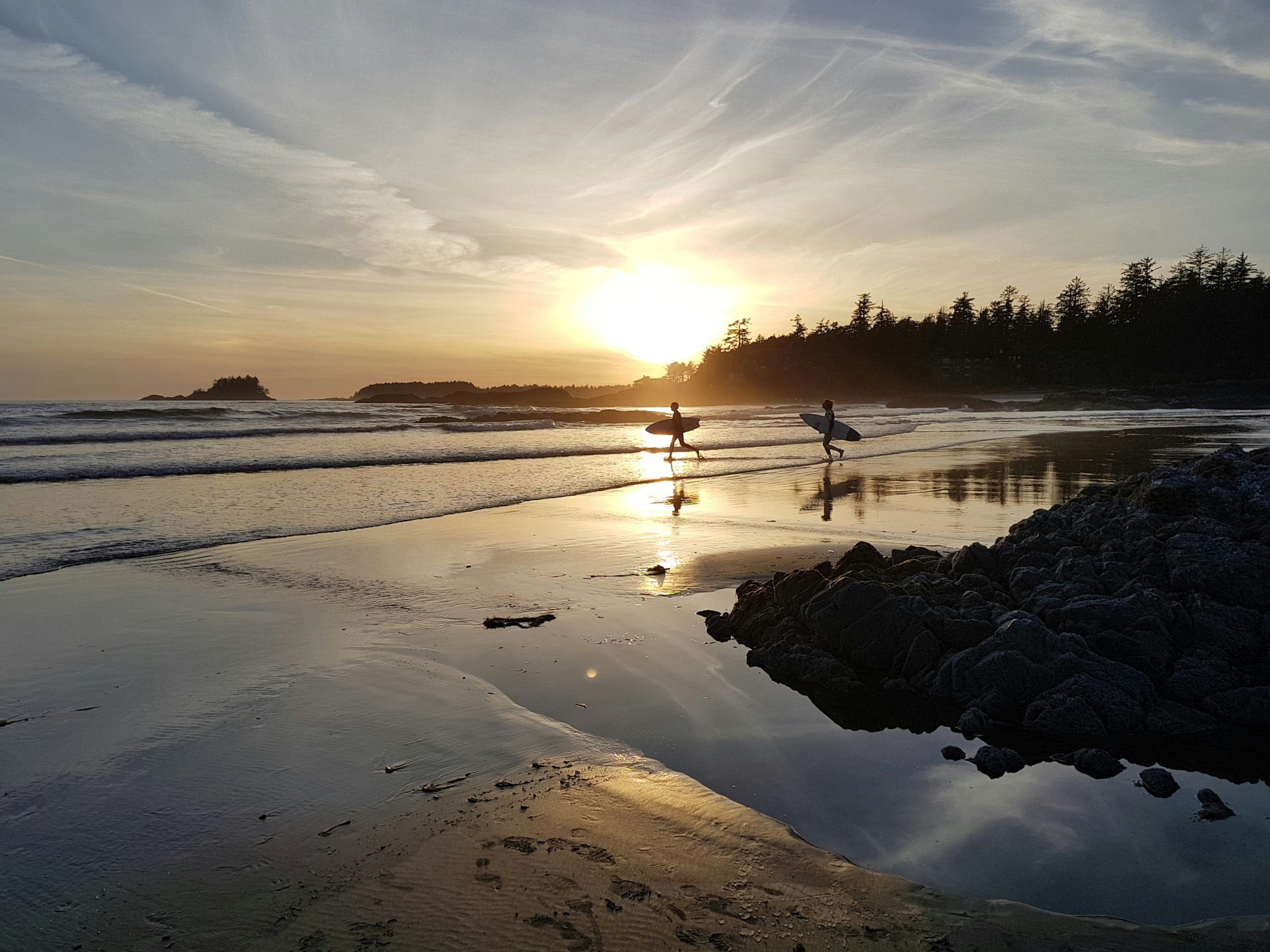 Surfers walking along Chesterman Beach, Tofino, British Columbia at sunset