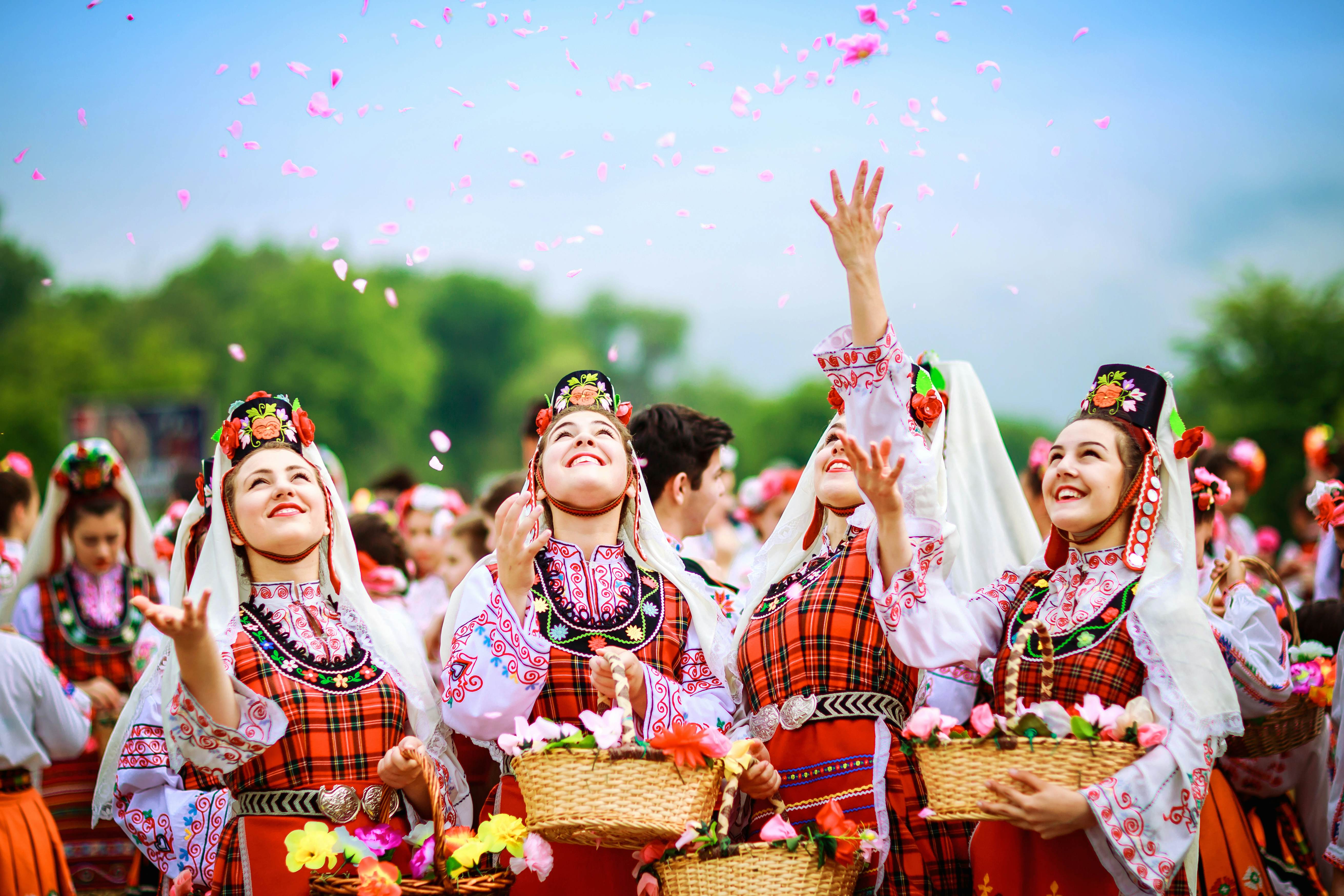 Four Bulgarian girls dressed in traditional clothing throwing rose petals in the air during the Annual Rose Festival in Kazanlak, Bulgaria.