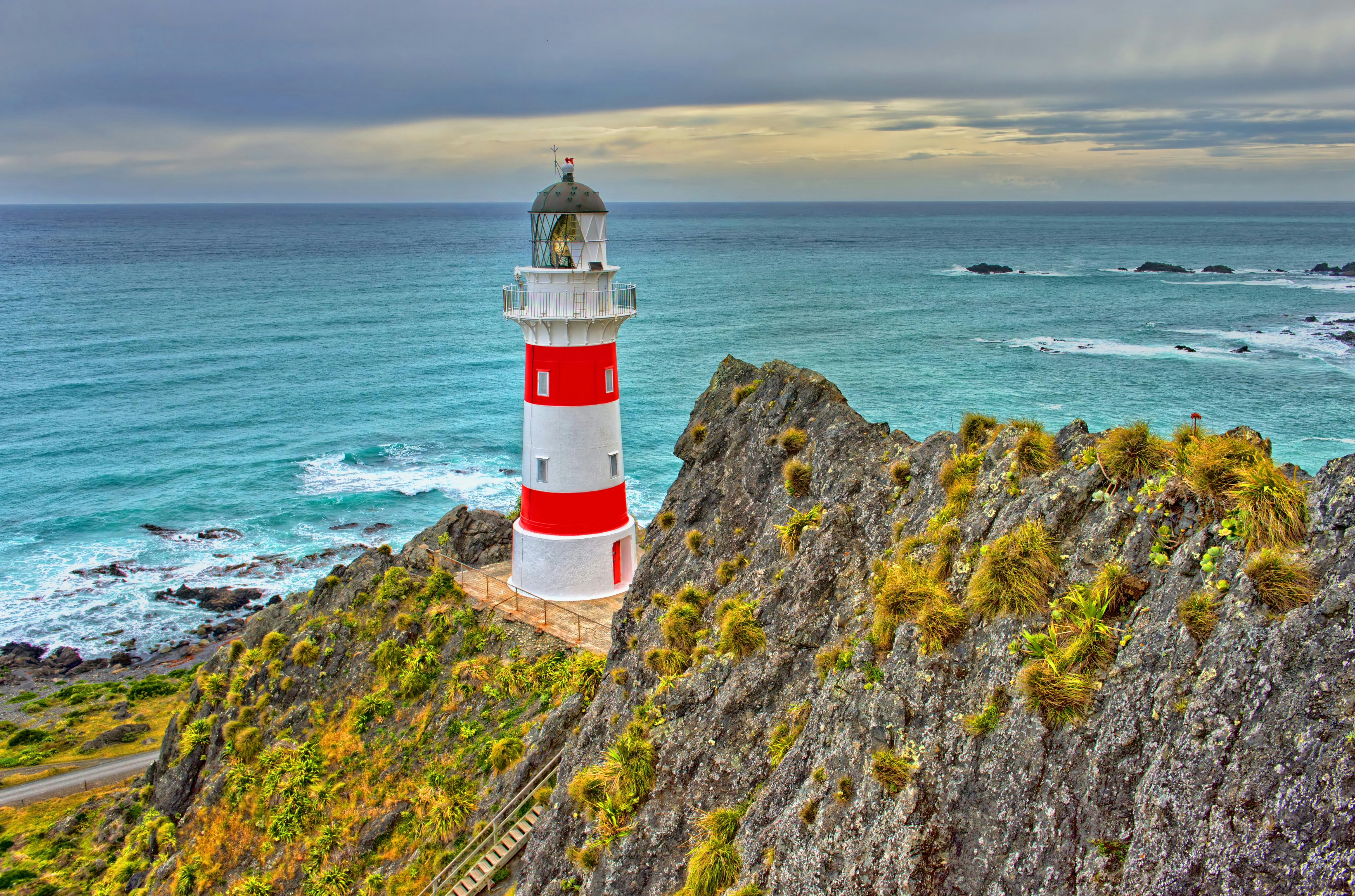 A red and white lighthouse on a rocky cliff