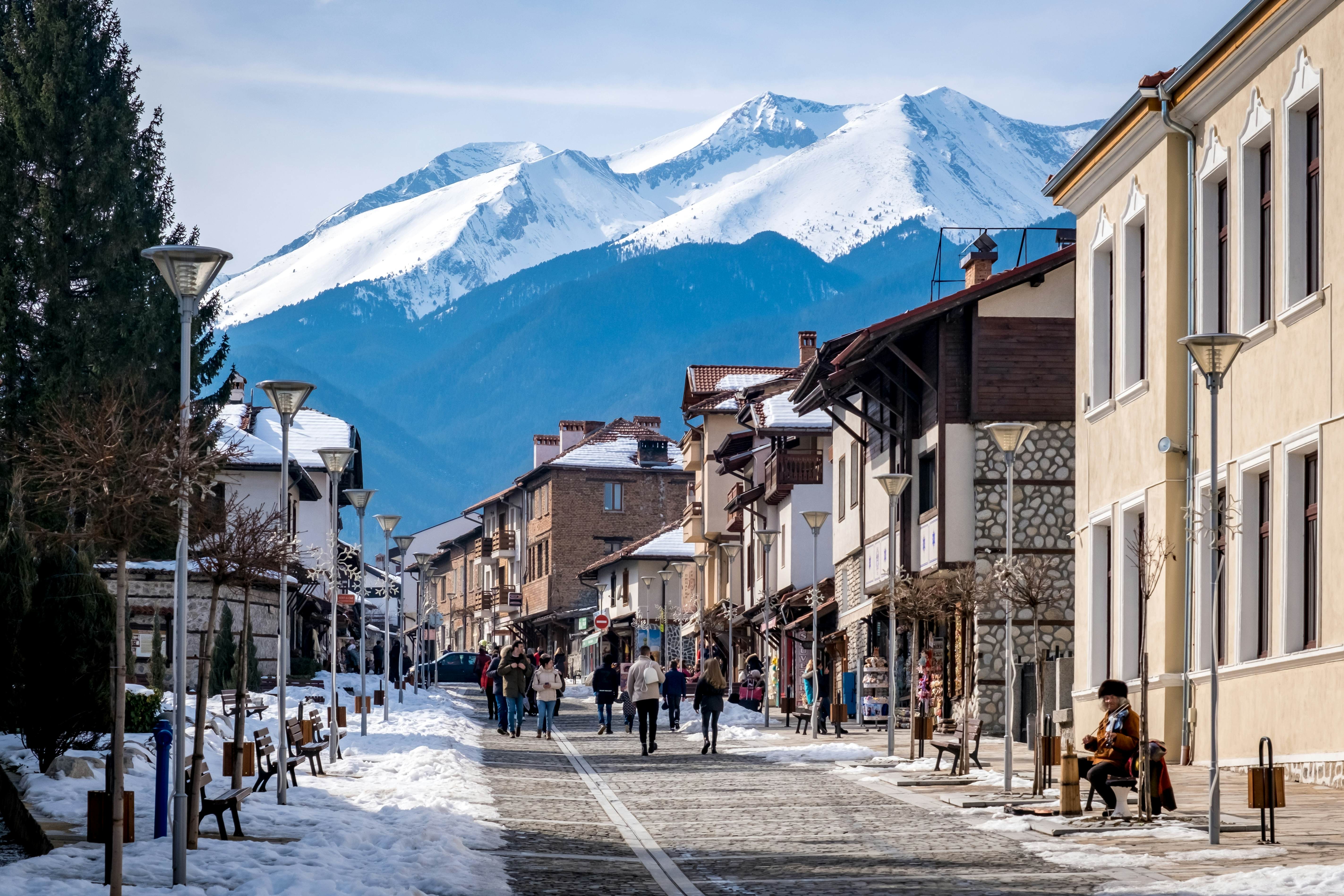 People walk up the snow-lined streets of a mountain town