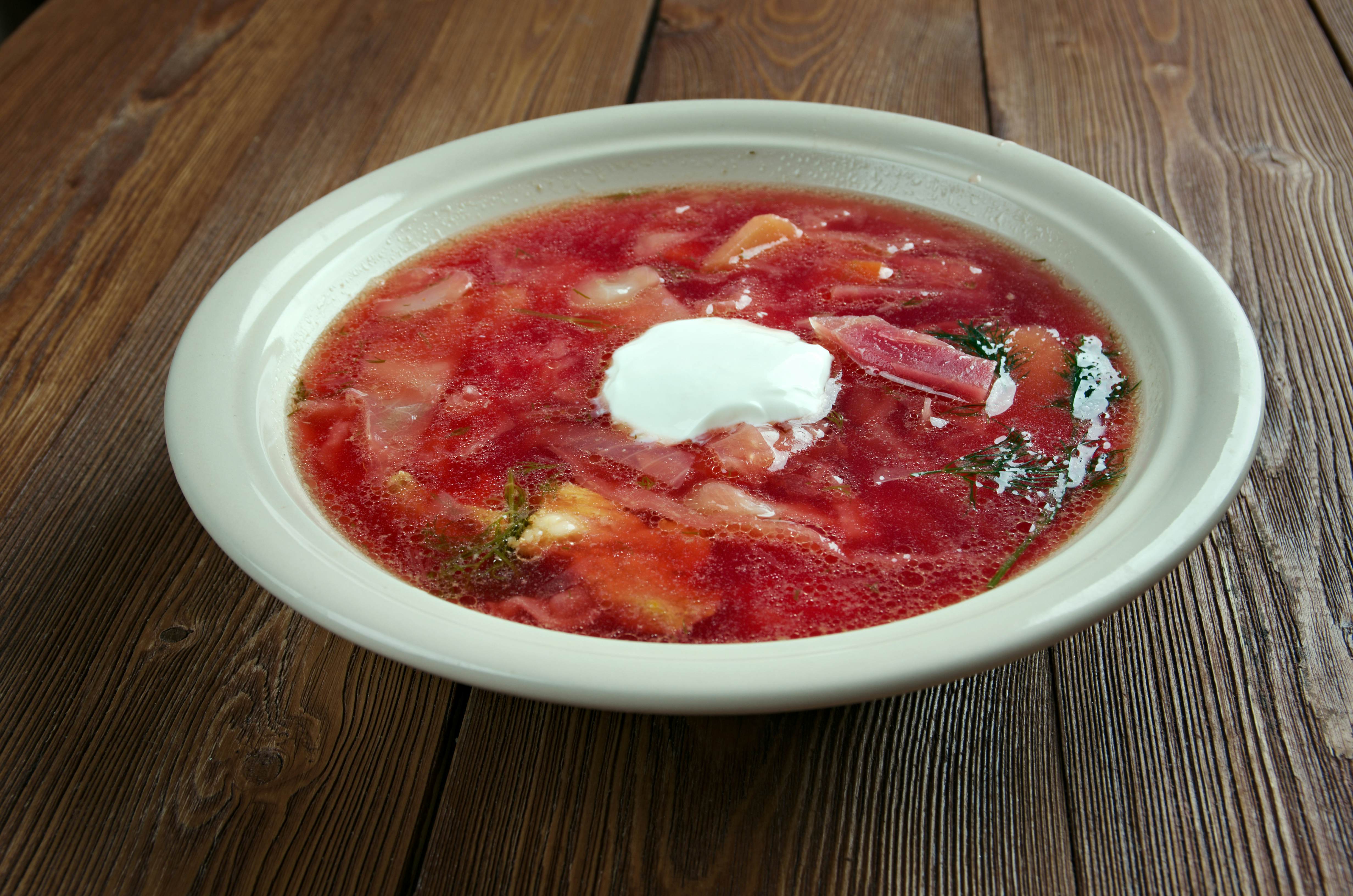 A bowl of Polish barszcz (beetroot soup) on a wooden table.