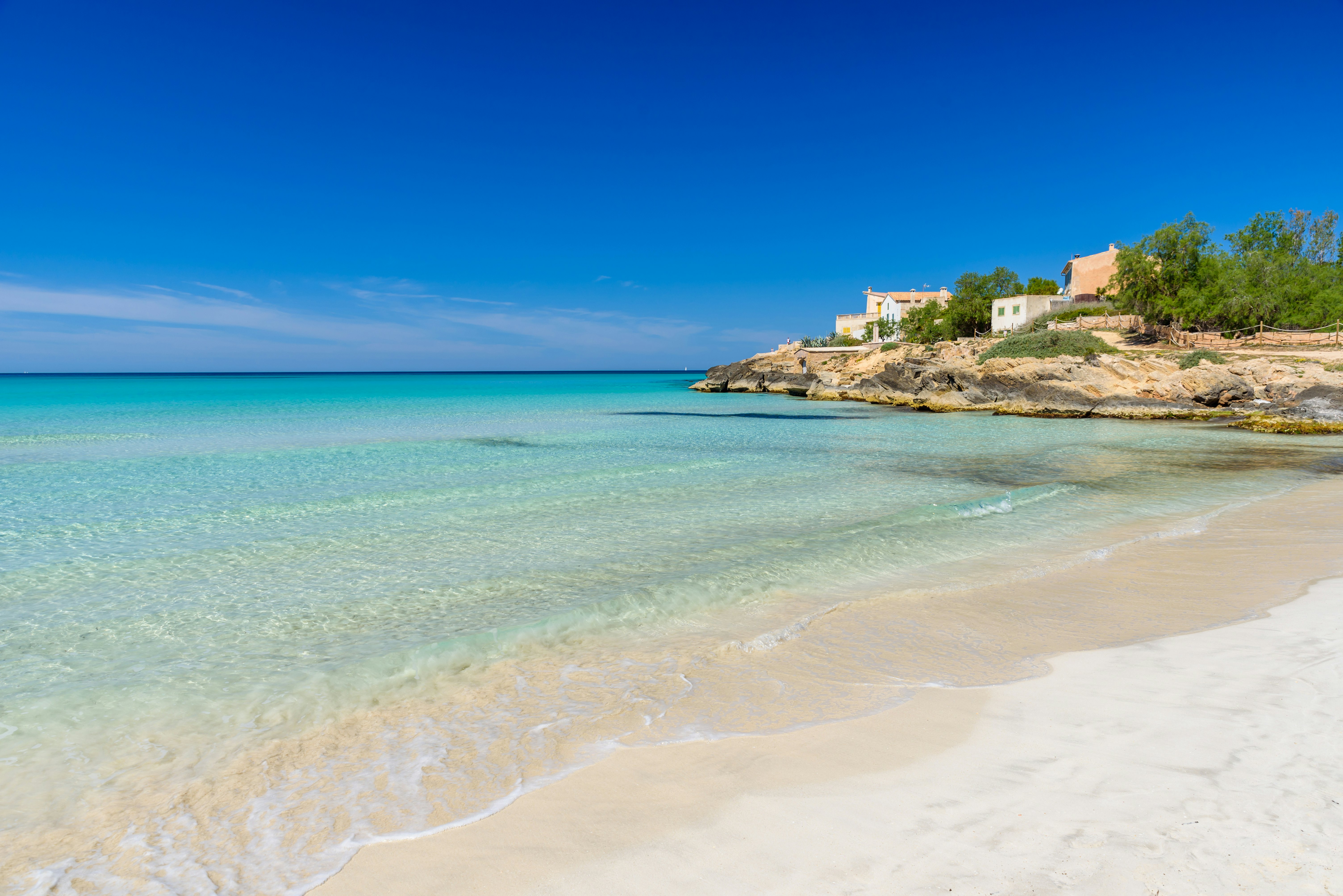 White sand beach with white washed houses overlooking it.