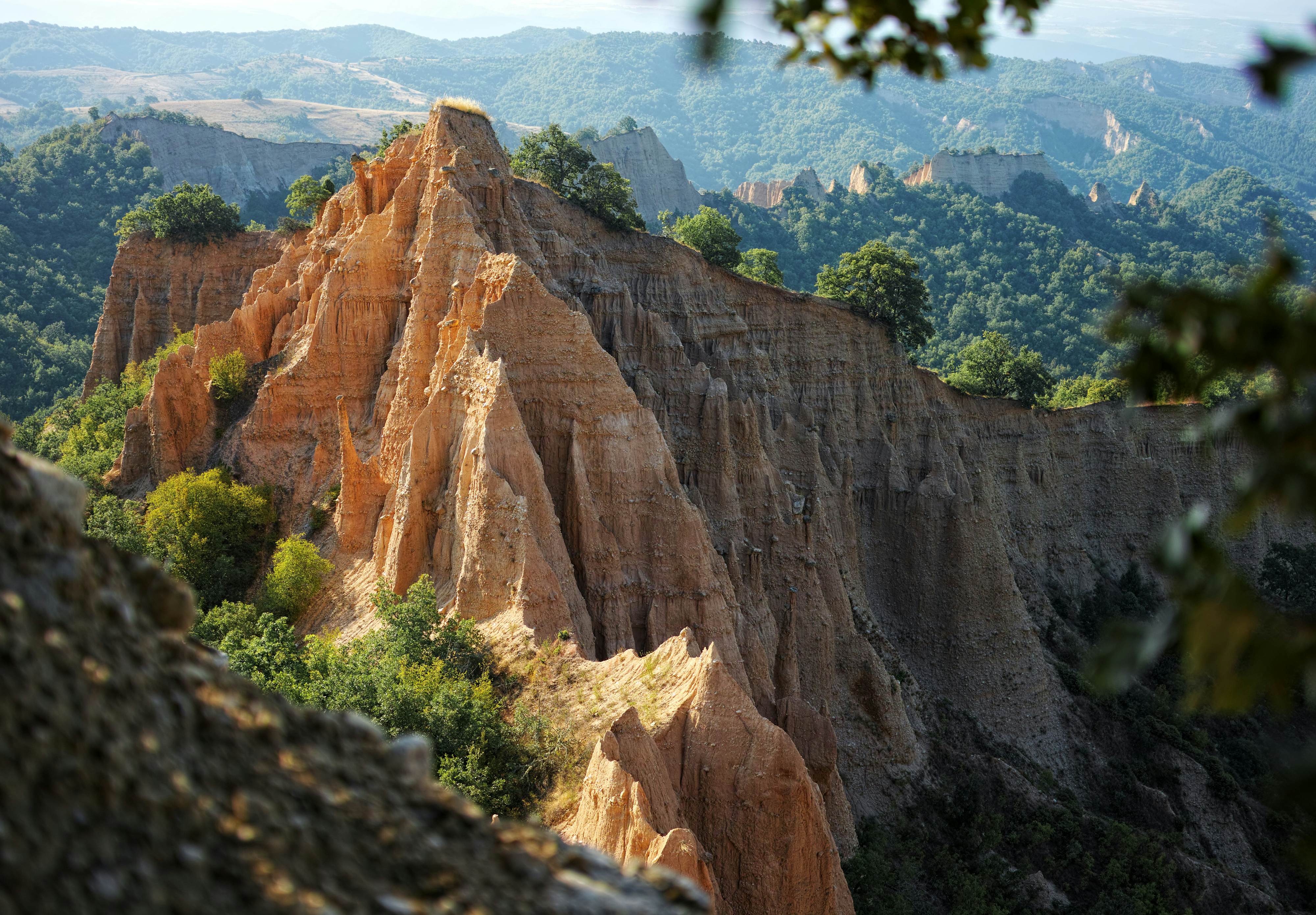 A vast landscape with large craggy sandy peaks covered by trees