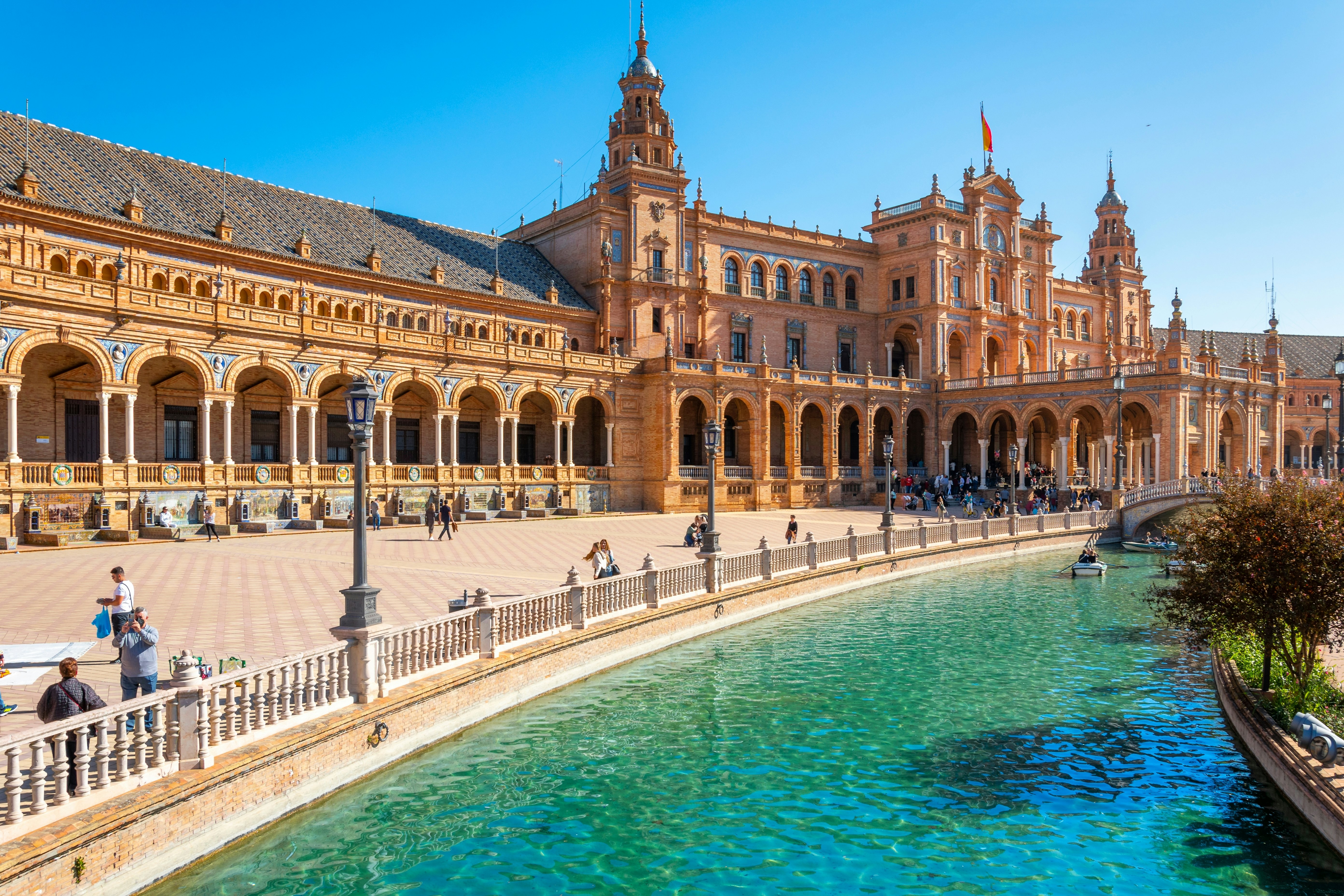 A summer day at the public Plaza de España park with tourists and locals enjoying boats in Seville