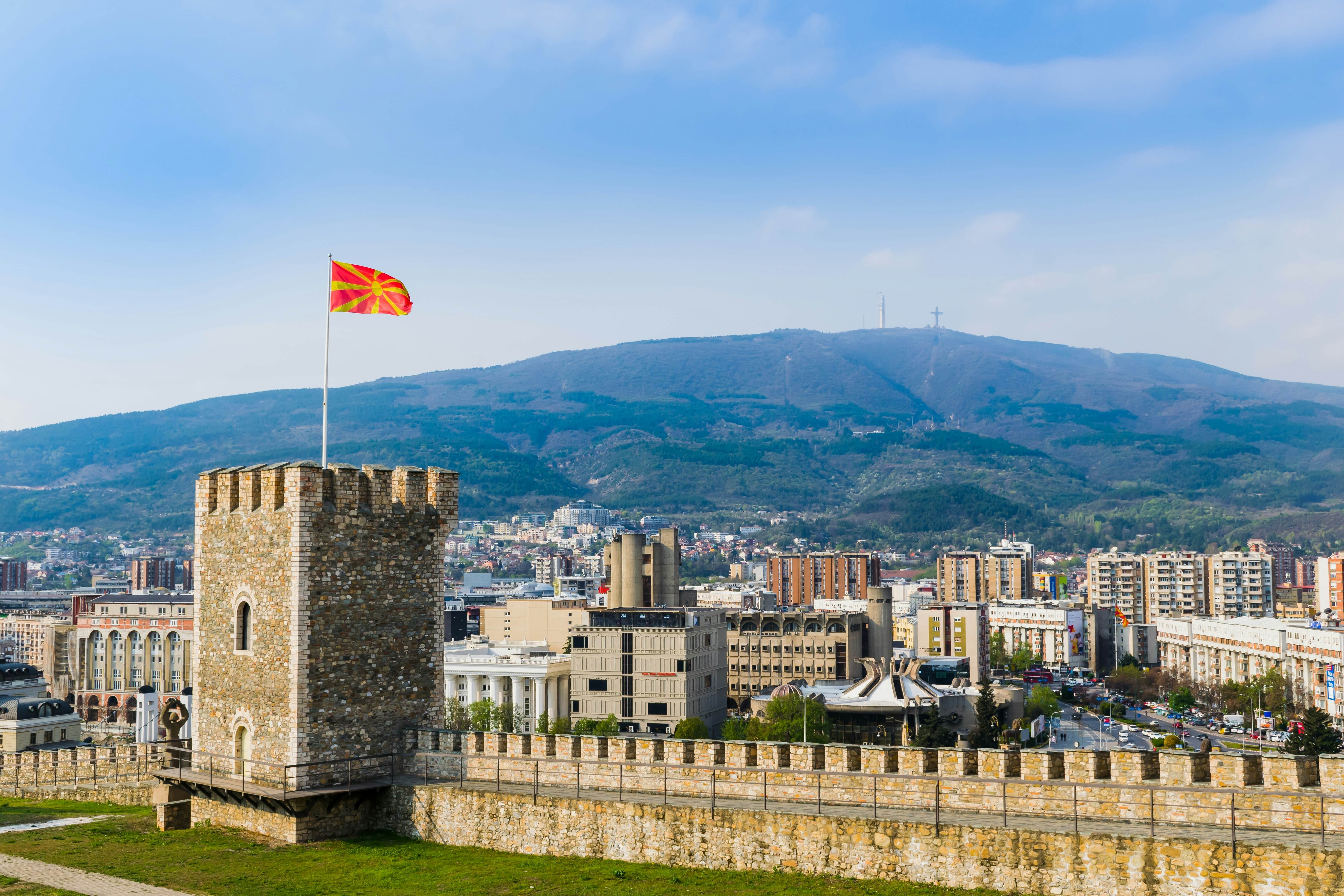 A large fortress tower flying the flag of Macedonia with a city backdrop