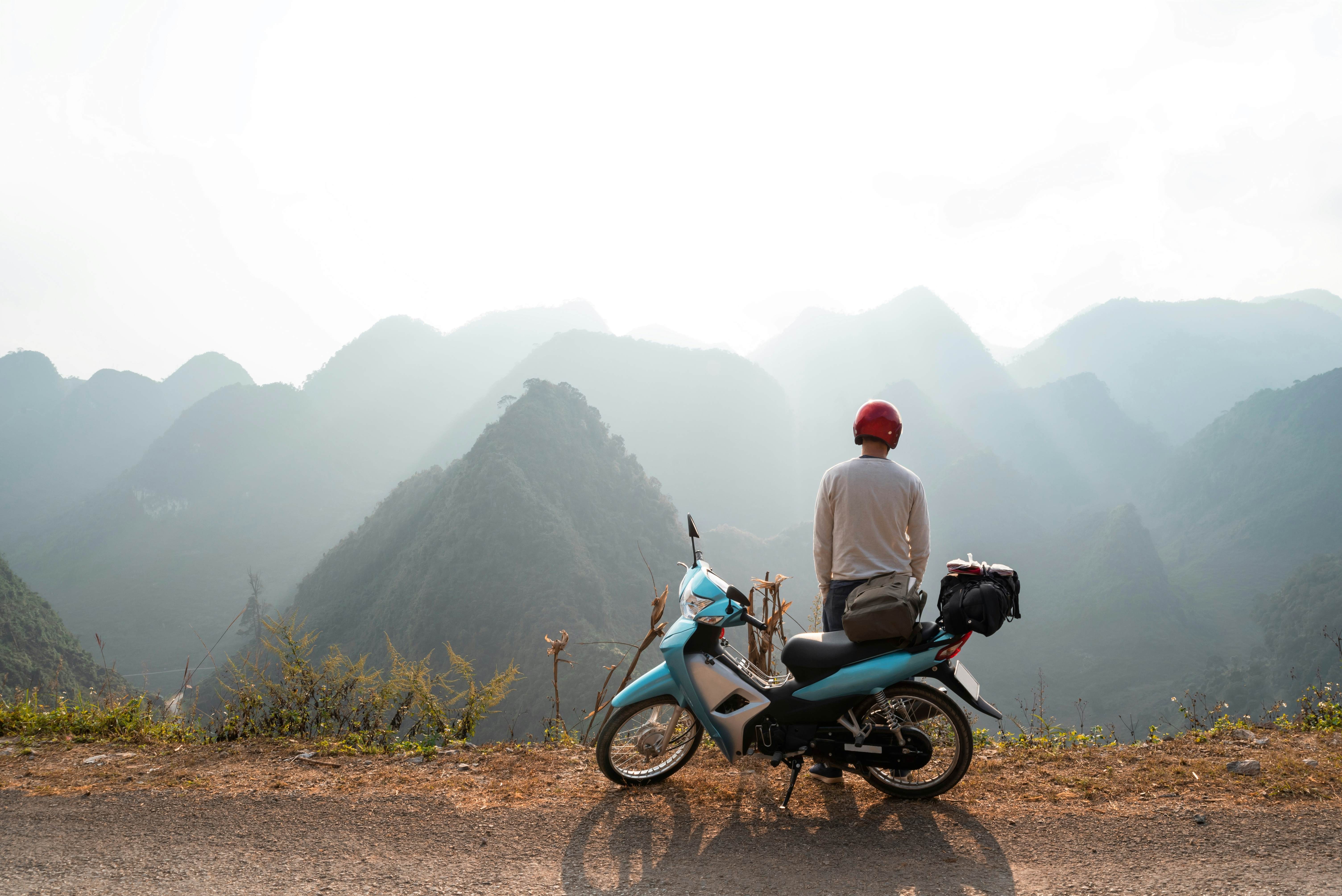 A backpacker enjoys the stunning views of the road and landscape on a motorcycle trip through a mountain pass