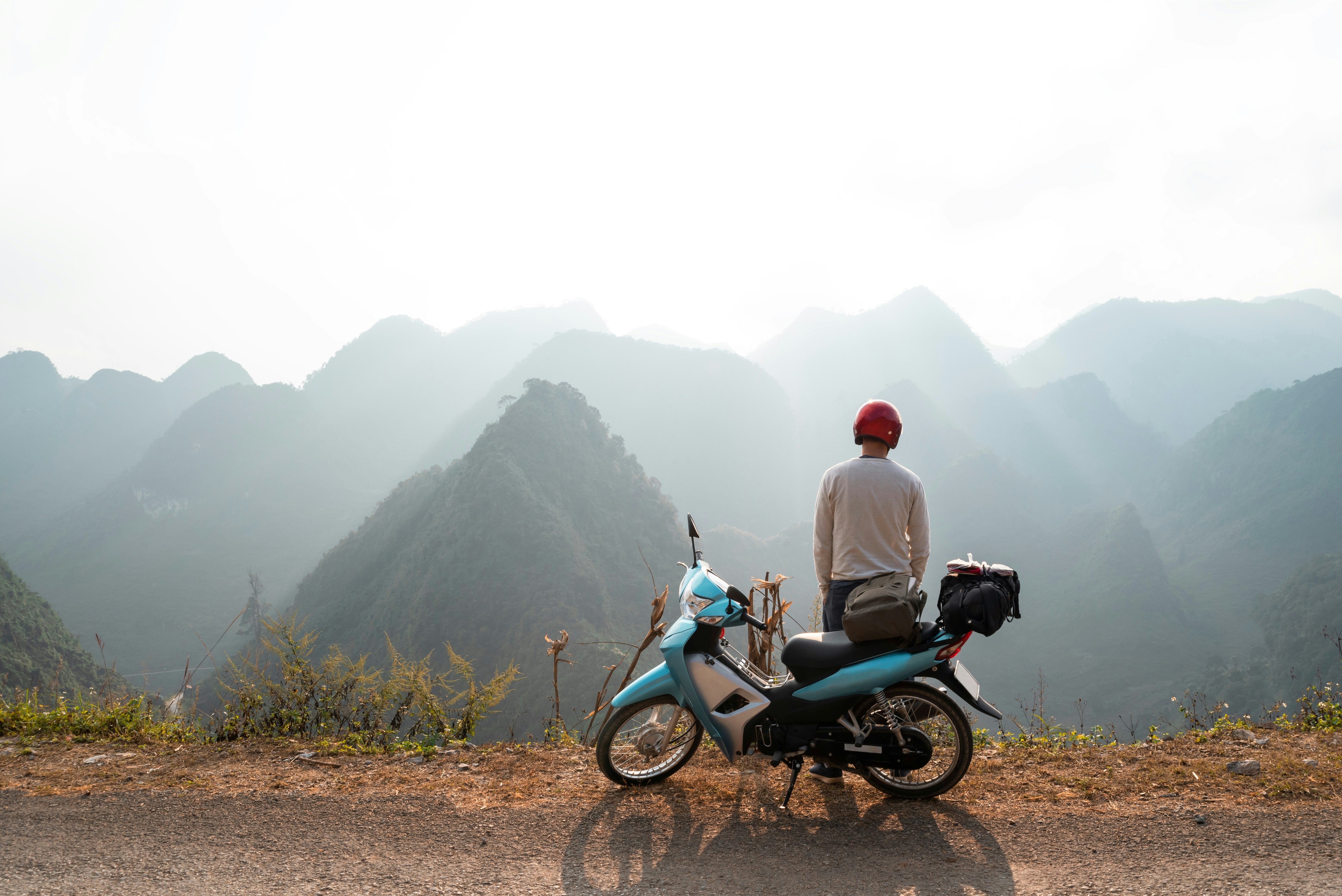 A backpacker enjoys the stunning views of the road and landscape on a motorcycle trip through a mountain pass