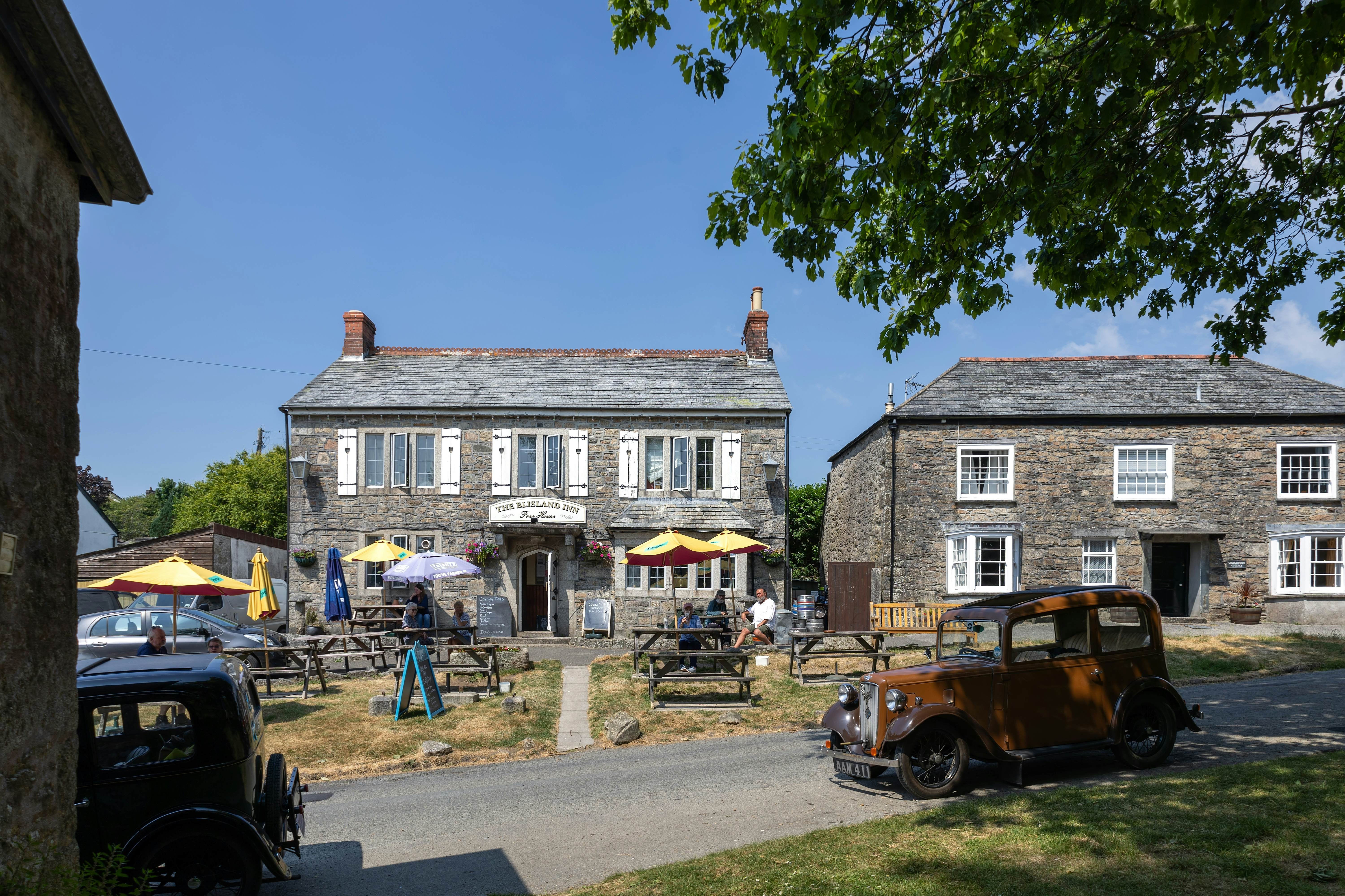 Austin Seven in front of the Inn in Blisland Cornwall, with picnic tables with umbrellas in the front yard