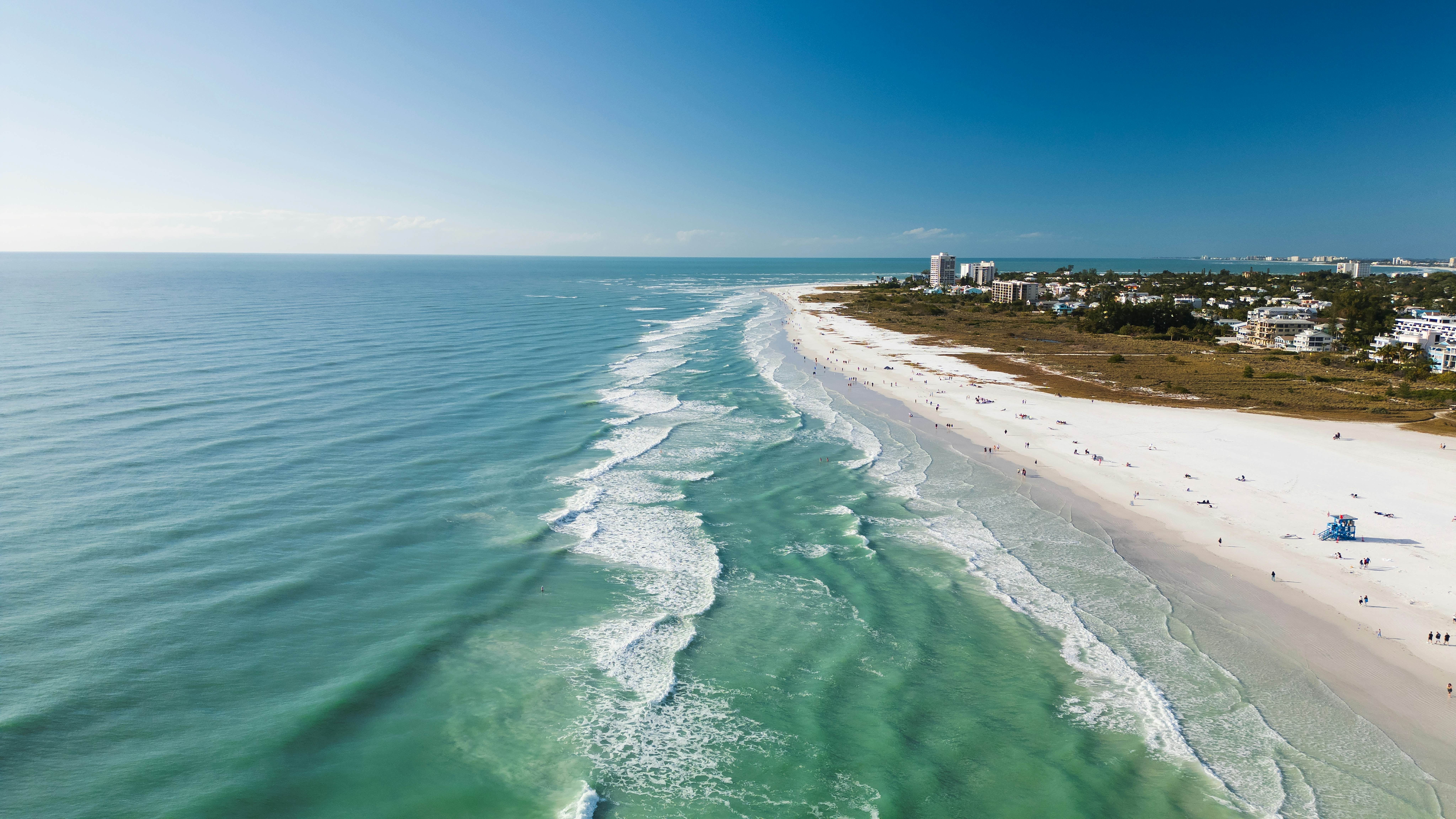 Drone Fly view over beach in Siesta Key,  Florida. Beautiful Siesta Key beach on a sunny day. Turquoise transparent water and blue sea in Siesta Key beach.