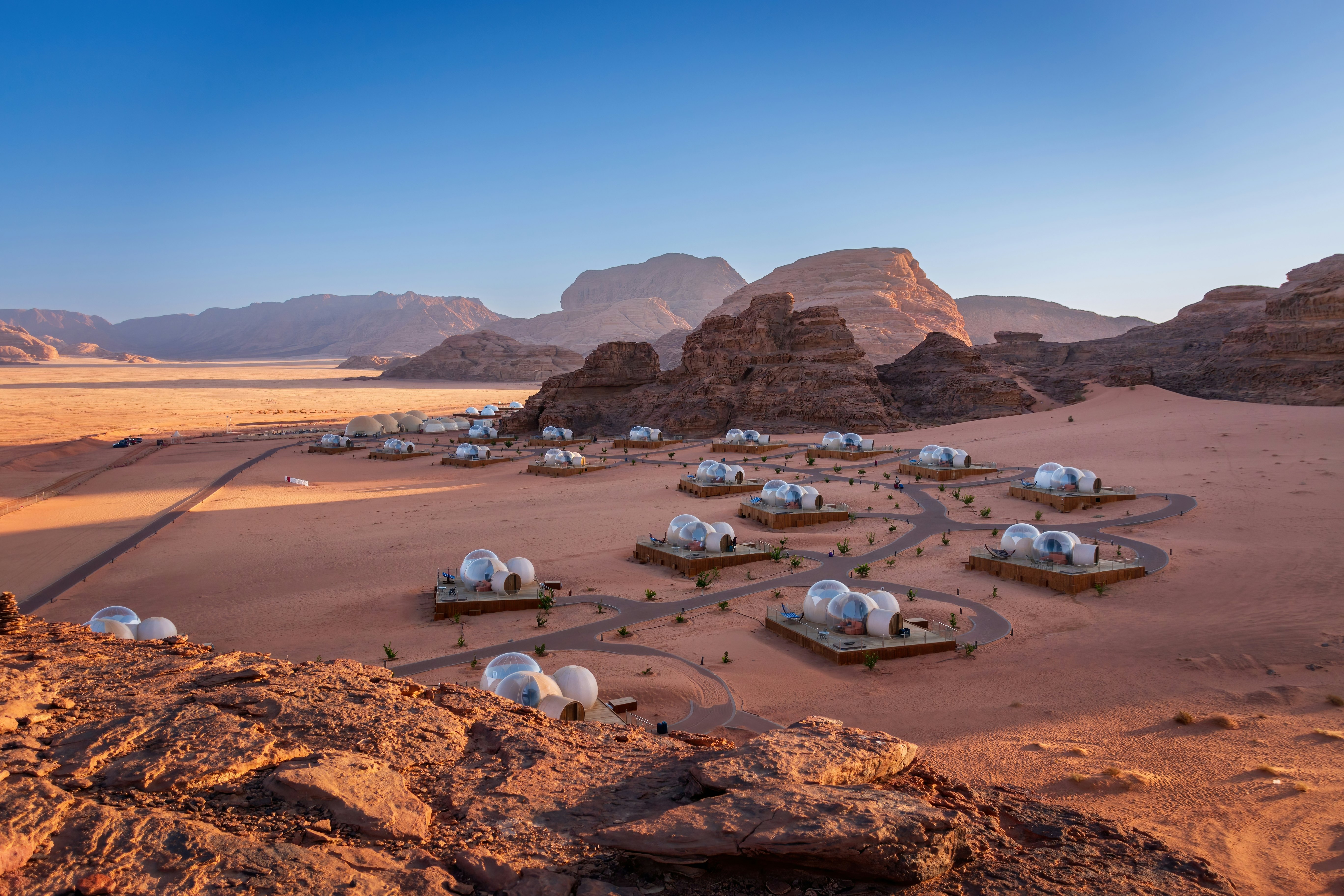 Scenic view of bubble tent camp at Wadi Rum desert in Jordan at sunrise against blue sky.