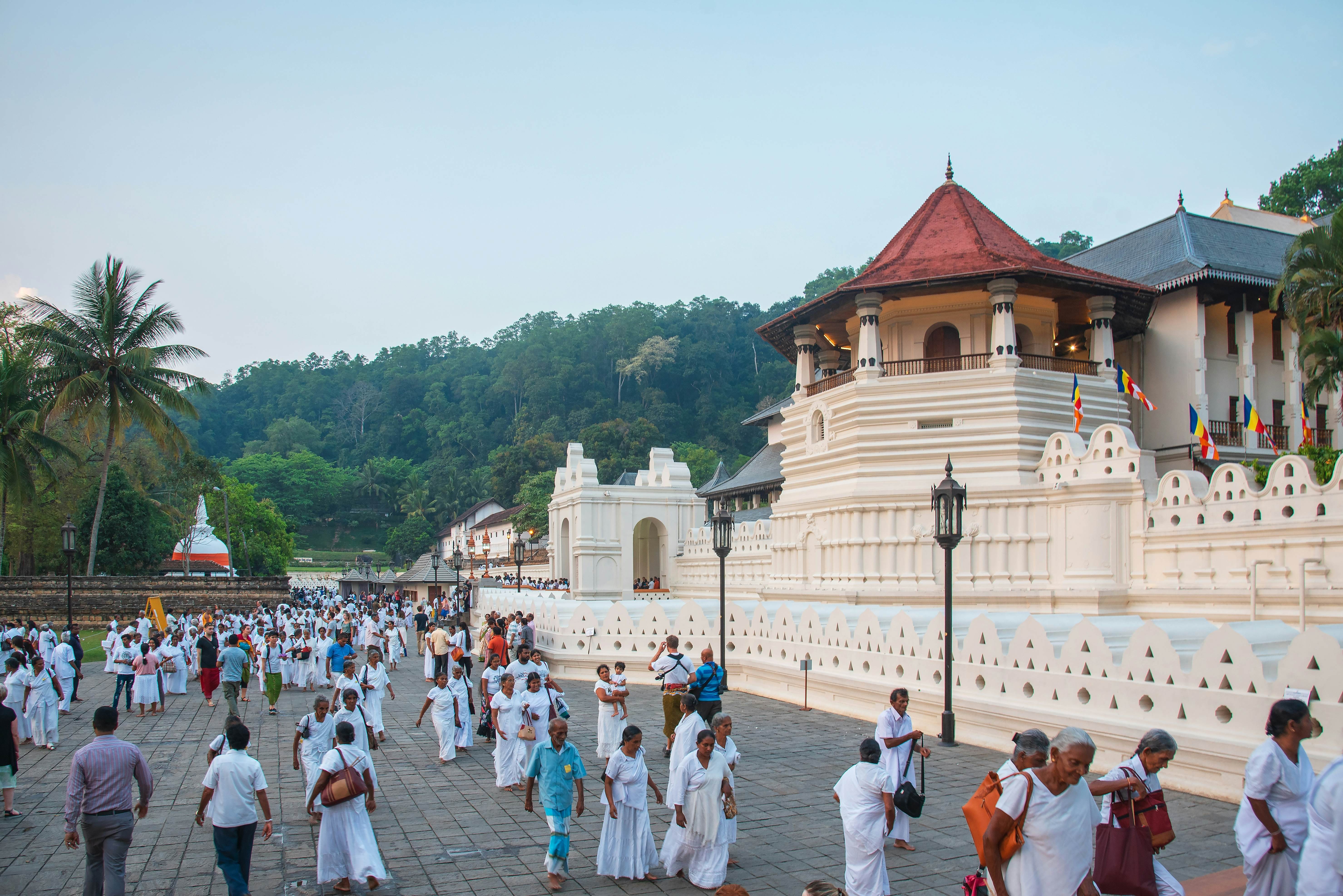 People, many dressed in white, outside a vast palace complex