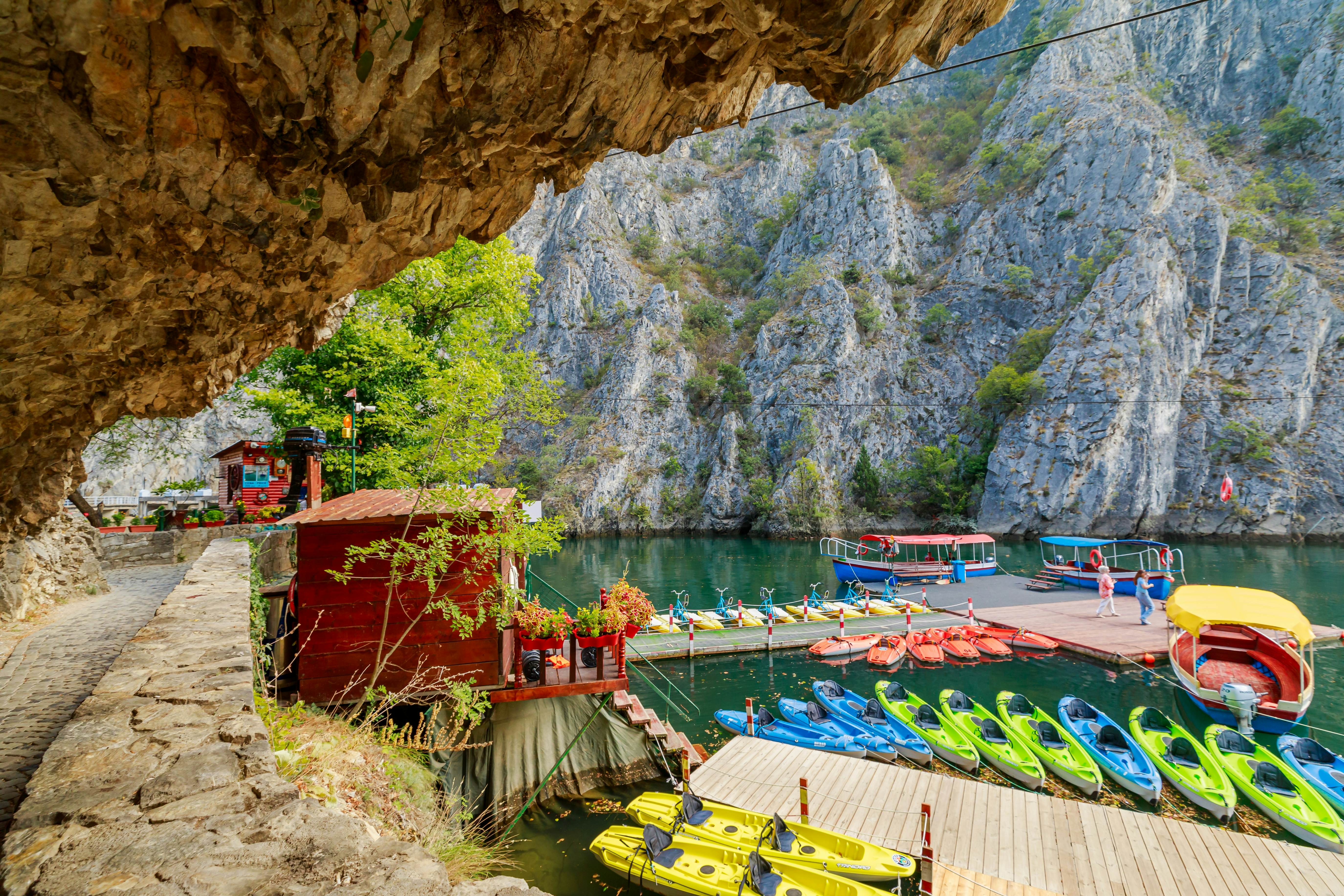 A series of kayaks docked off a wooden deck in a canyon