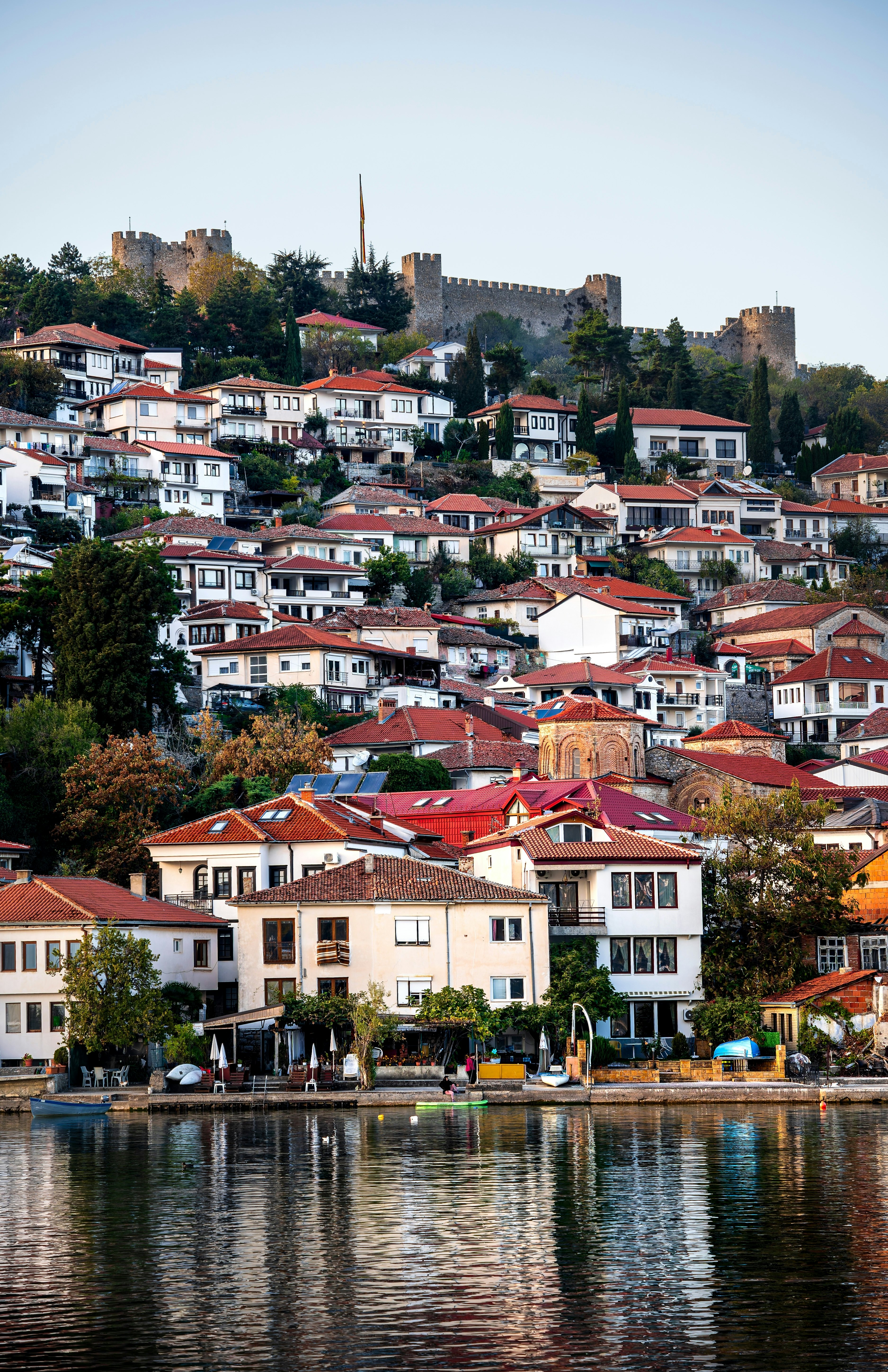 A lakeside town of traditional houses rises up a hillside to a fortress at the top